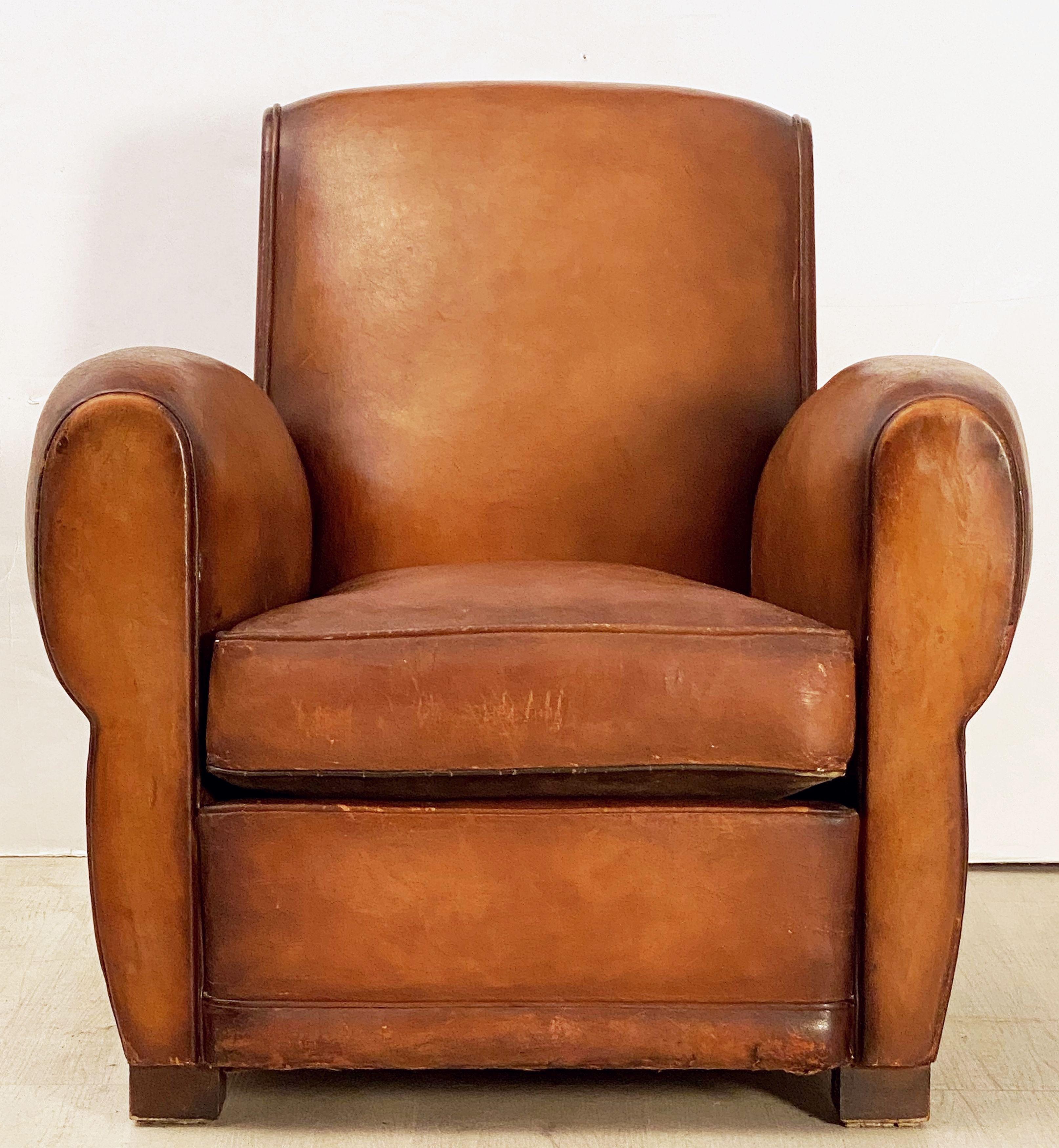 A handsome vintage French leather upholstered club or lounge chair from the Art Deco era - featuring a comfortable back and seat with removable cushion, with stylish arms and original leather, brass nail-head trim to back, and resting on shaped