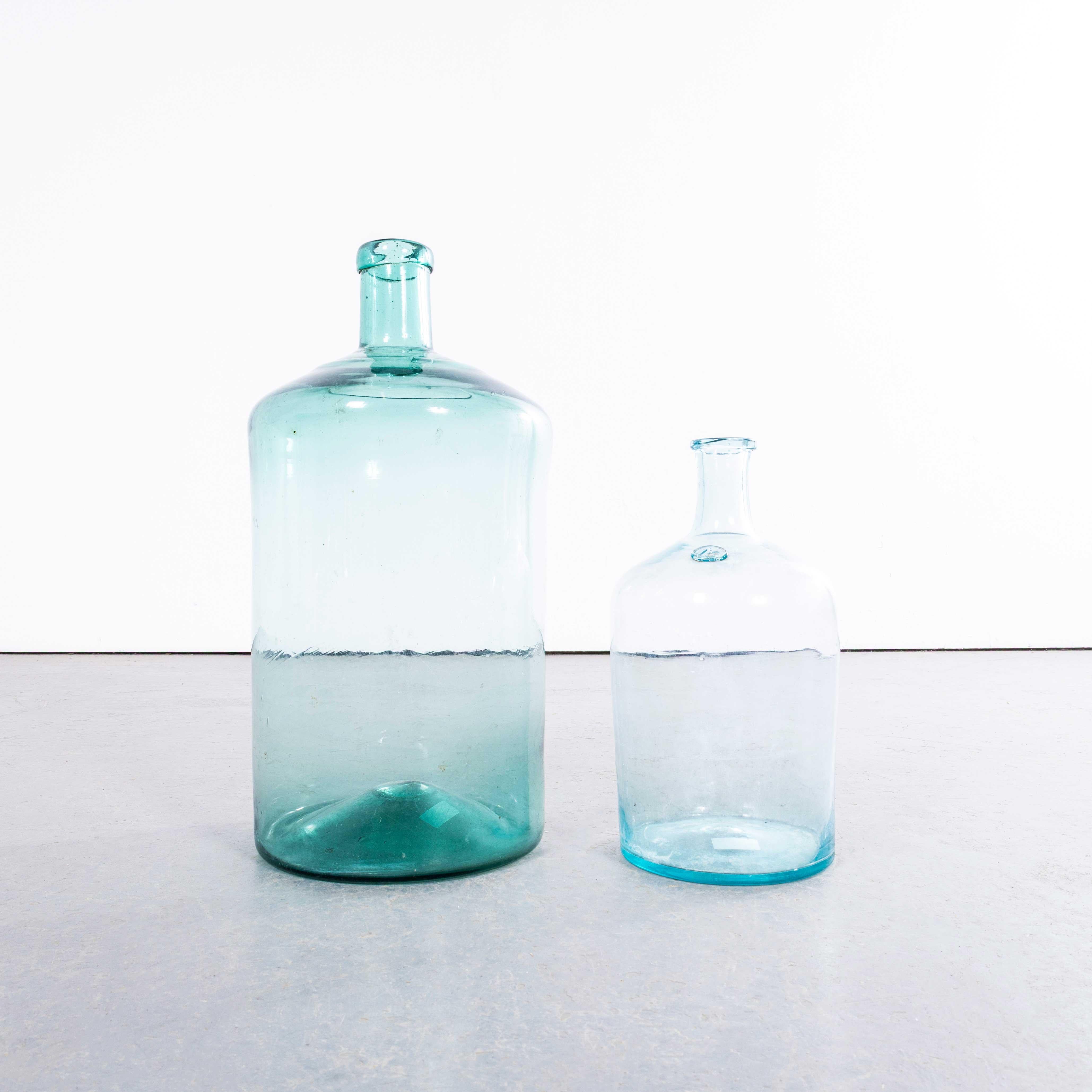 Damigiane francesi d'epoca in vetro blu e verde chiaro - Coppia. 

Una coppia di damigiane in vetro soffiato a bocca utilizzate come contenitori tradizionali principalmente per la conservazione e il trasporto del vino. Queste damigiane sono state