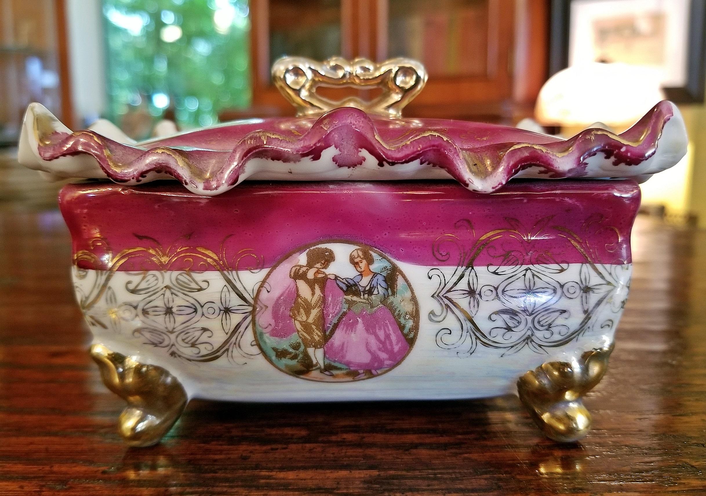 Nice vintage French Limoges style lustre porcelain box with lid.

Purple and white in color with rippled edging and with gold gilding to handle and legs.

Lady and gent scenes.

Probably late 19th century, circa 1890.

No marks.

Very
