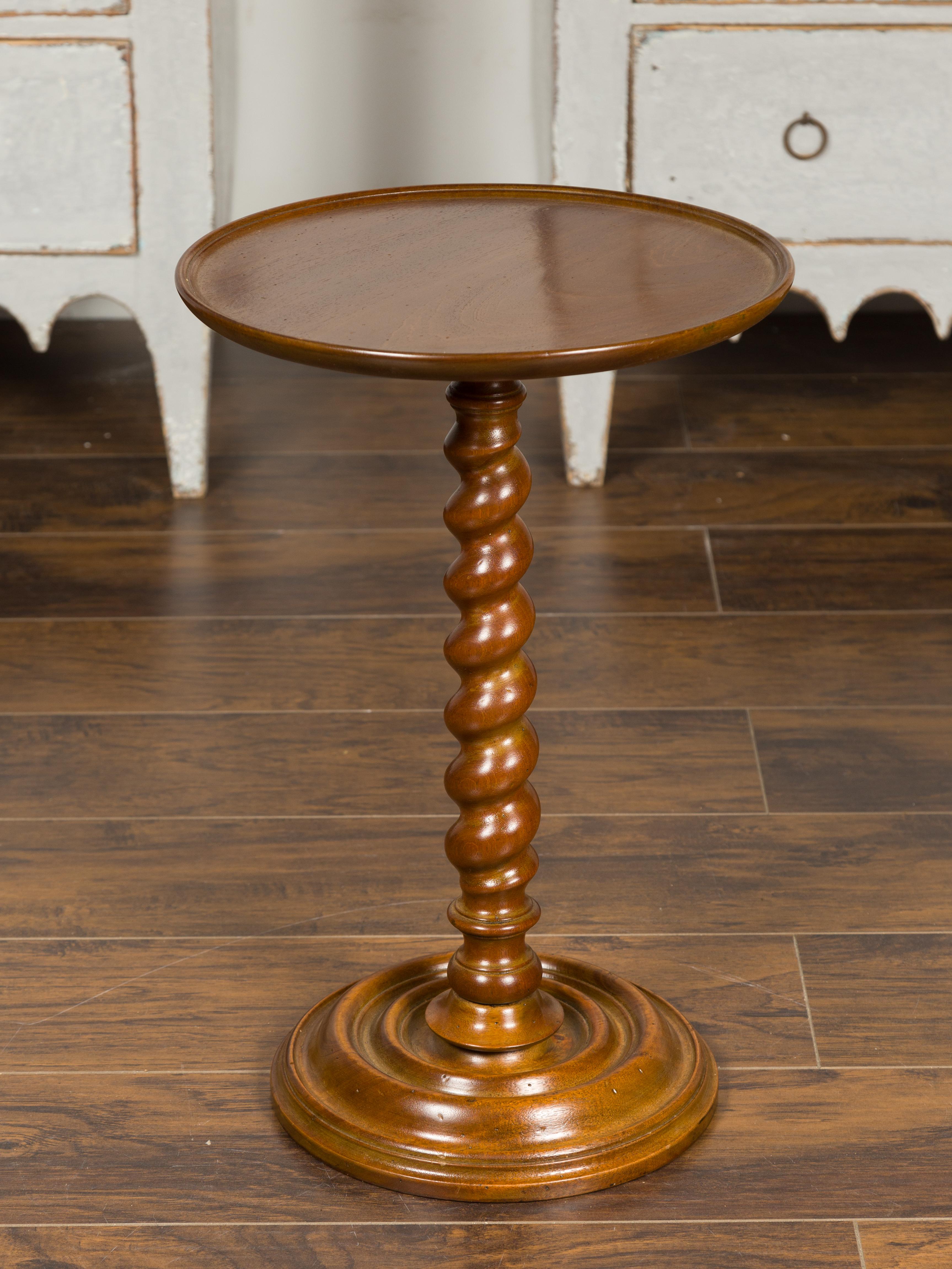 A French Louis XIII style wooden side table from the mid-20th century, with circular top and barley twist pedestal base. Born in France during the mid-century period, this small side table features a round tray top, sitting above an eye-catching