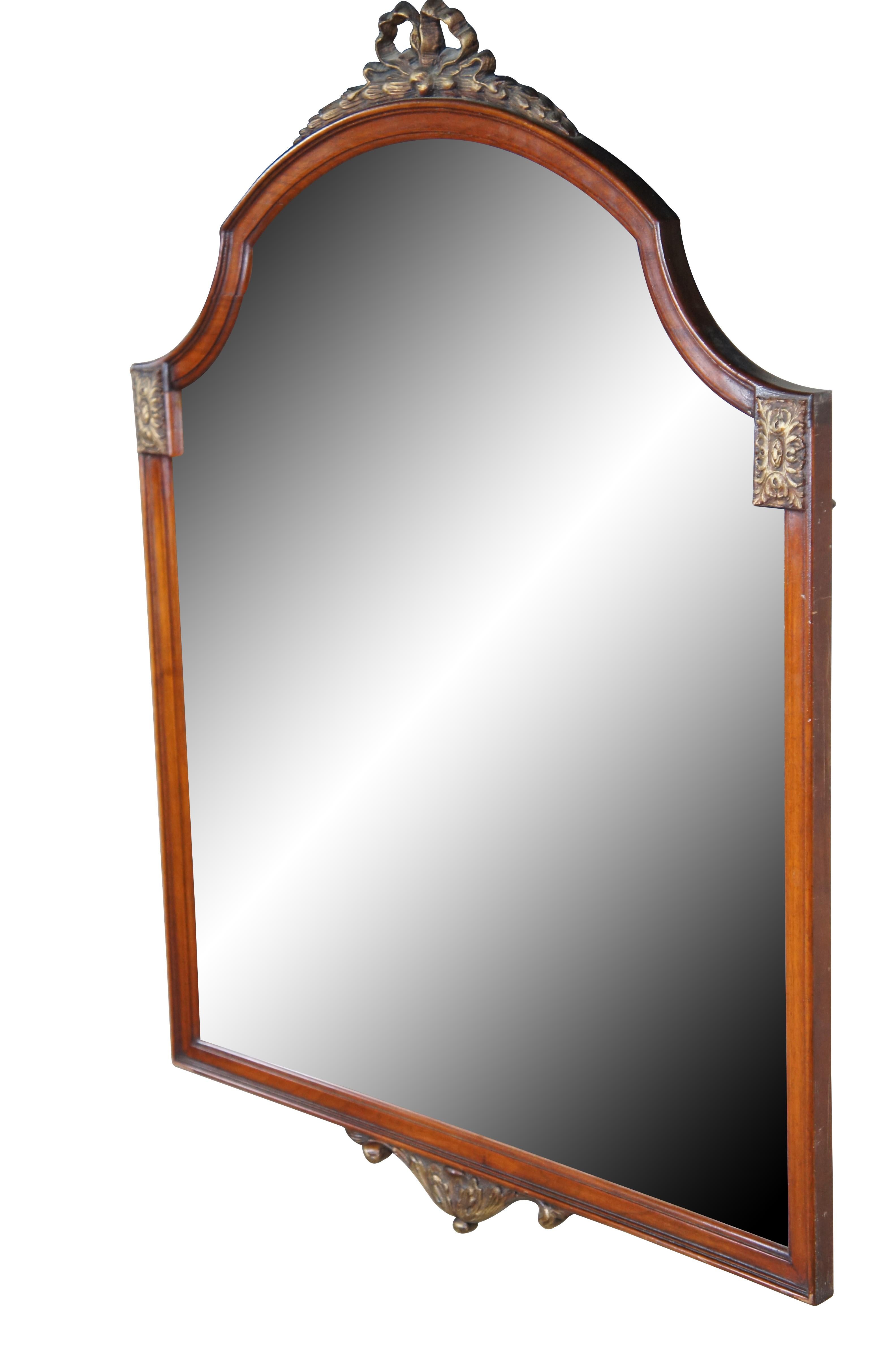 Specchio da parete in mogano in stile Luigi XV del XX secolo.  Presenta una cornice di forma rettangolare con piano sagomato e arcuato con accenti neoclassici a nastro e medaglioni francesi.  Il lato inferiore presenta un abbellimento svasato ad