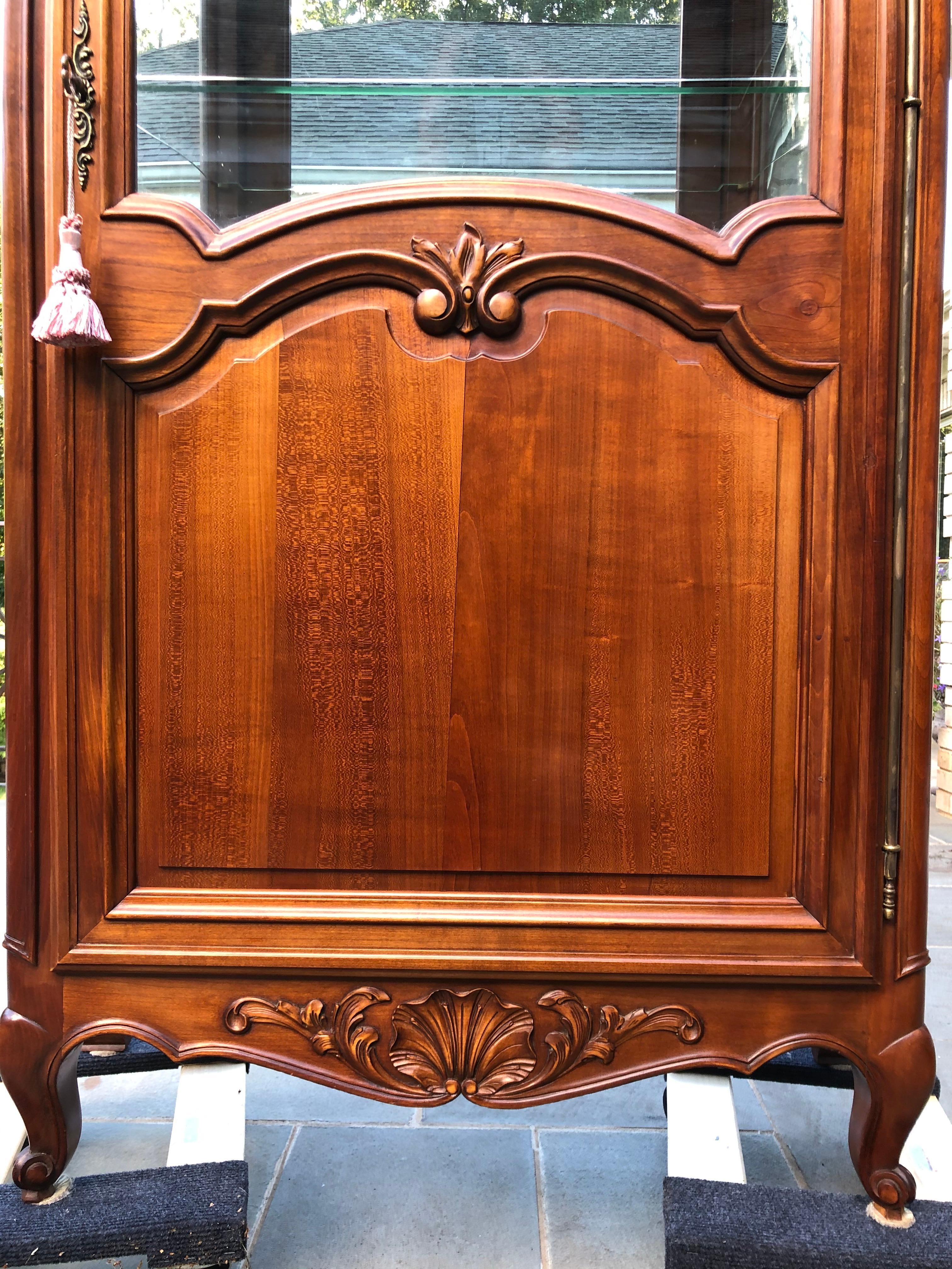 Elegant French cherry curio cabinet. With beveled glass front and sides, all your collectibles will be well displayed in this Louis XV-style curio. This piece features rich carvings and all brass original hardware. Mint condition.