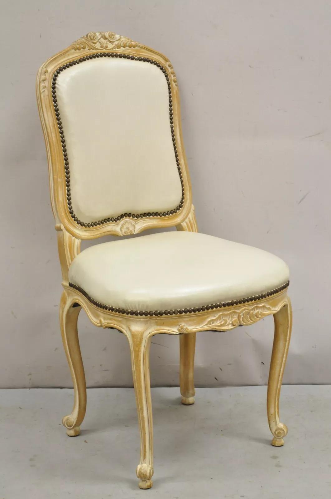 Sedie da pranzo vintage in stile Luigi XV - Set di 4. L'articolo presenta una struttura in legno massiccio intagliato, una finitura bianca anticata, un rivestimento in Naugahyde bianco sporco, un grande stile e una grande forma. Circa metà del XX