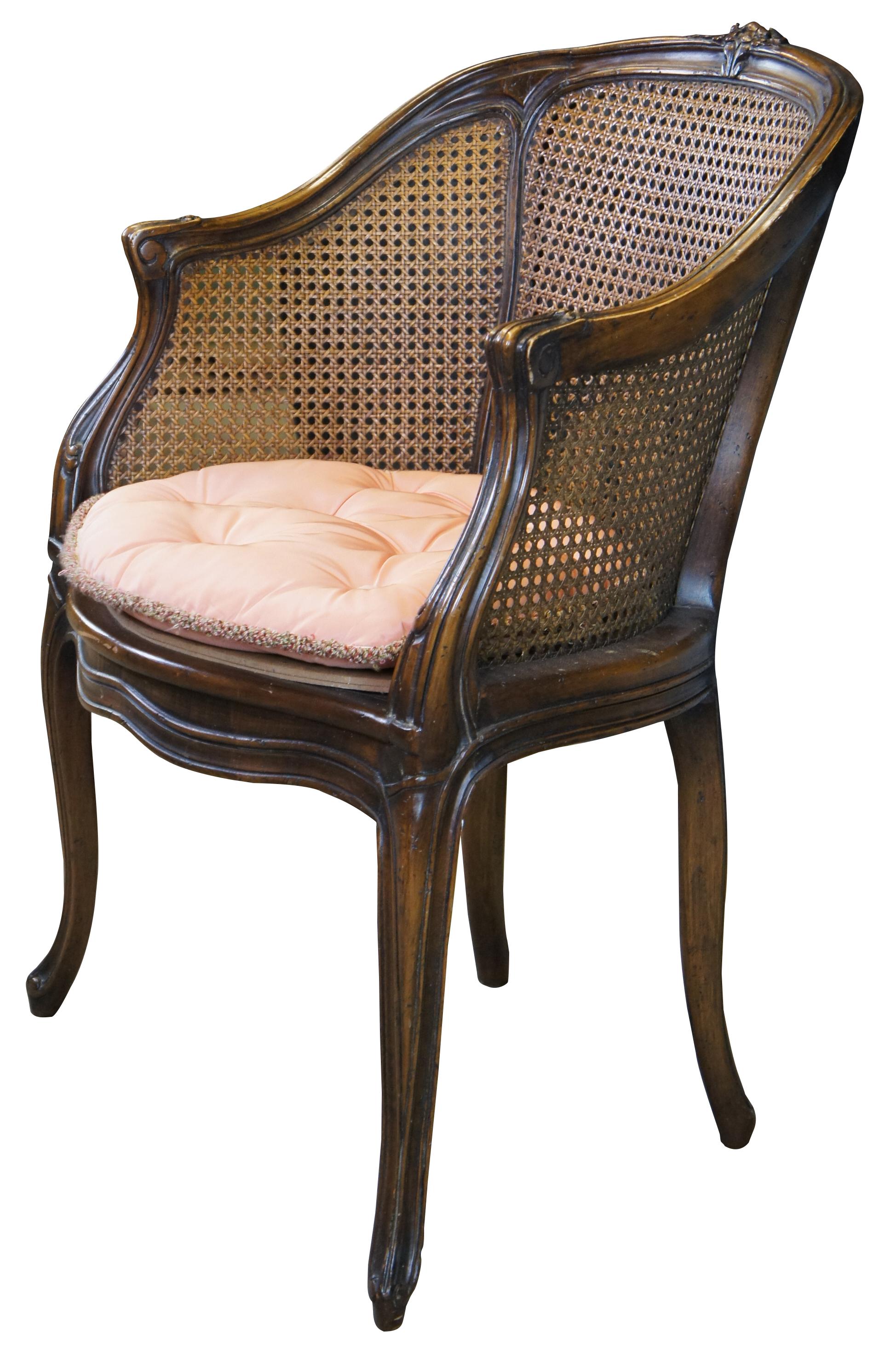 Vintage French Louis XVI style Bergere armchair. Made of walnut featuring serpentine barrel form with caned sides and back, fluted accents, and carved flower.
 