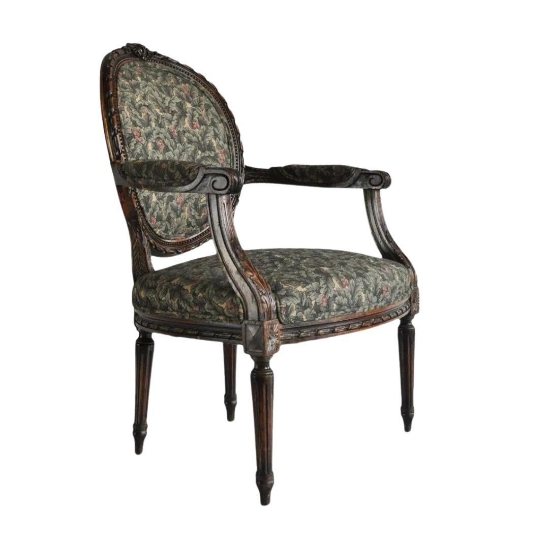 Vintage French Louis XVI Style Carved Walnut Fireside Arm Chair Fauteuil. Item features beautiful carved scrollwork-acanthus arms, small florets along the back, carvings the entire way around the oval balloon back, and fluted column-form legs. Circa