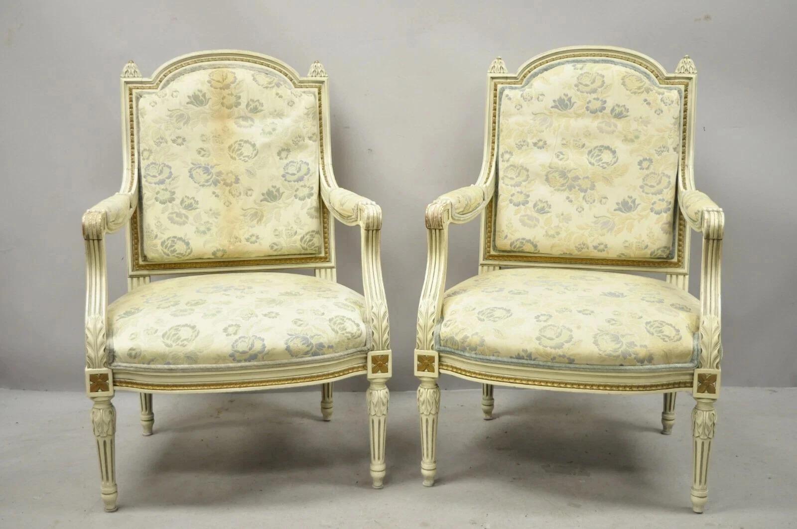 Poltrone da salotto francesi d'epoca in stile Luigi XVI dipinte a crema e dorate - Coppia. L'articolo è caratterizzato da una struttura in legno massiccio, braccioli imbottiti, finitura anticata, dettagli ben intagliati, gambe affusolate, grande