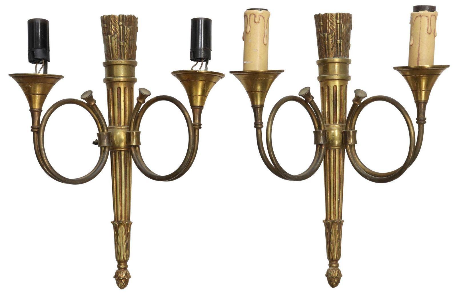 Vintage French Louis XVI style gilt metal two-light wall sconces, 20th c. These sconce feature wall plate modeled as a quiver of arrows, each issuing two hunting horns, ending in faux candles, (one) lacking candle covers. The lights are in need of