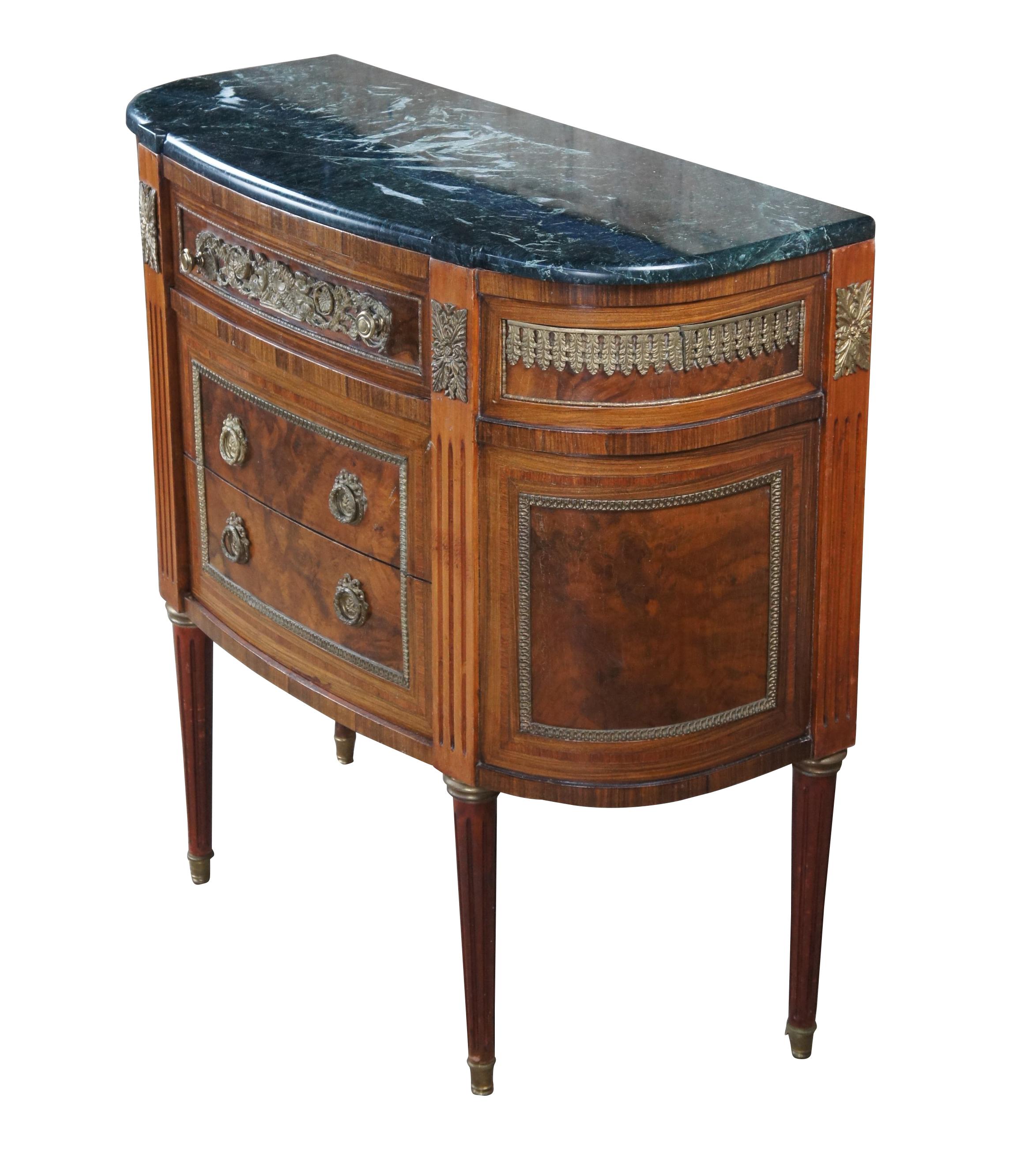 Vintage French Louis XVI style commode, dresser or console, circa 1970s.  Made of mahogany featuring half round demilune form with ornate brass trim, notched marble top, three drawers, fluted accents and tapered legs capped with brass feet.  Made in