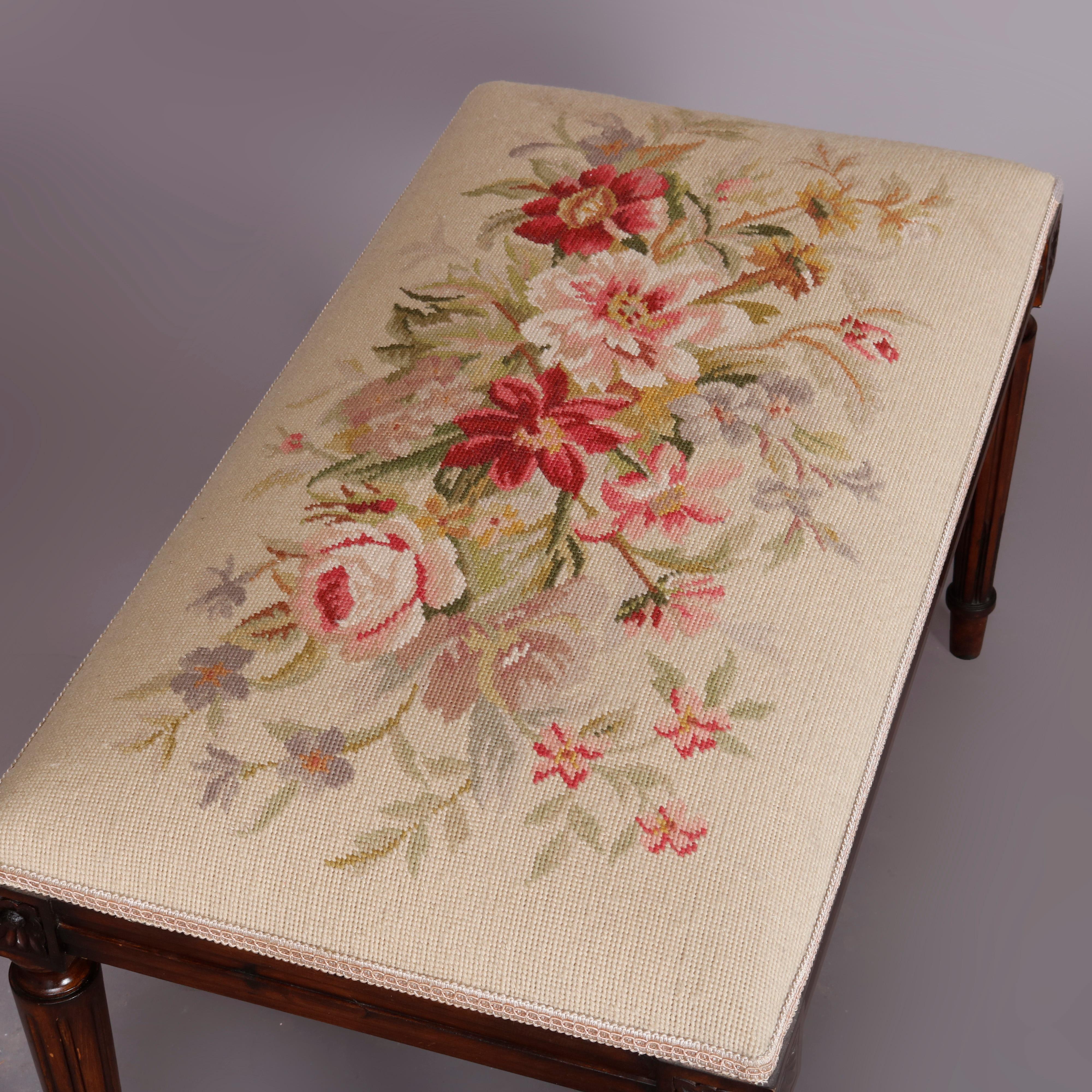 A vintage French Louis XVI style piano bench offers mahogany construction, raised on tapered and fluted legs with rosette joints and surmounted by seat having floral needlepoint upholstery, circa 1930

Measures: 19.5