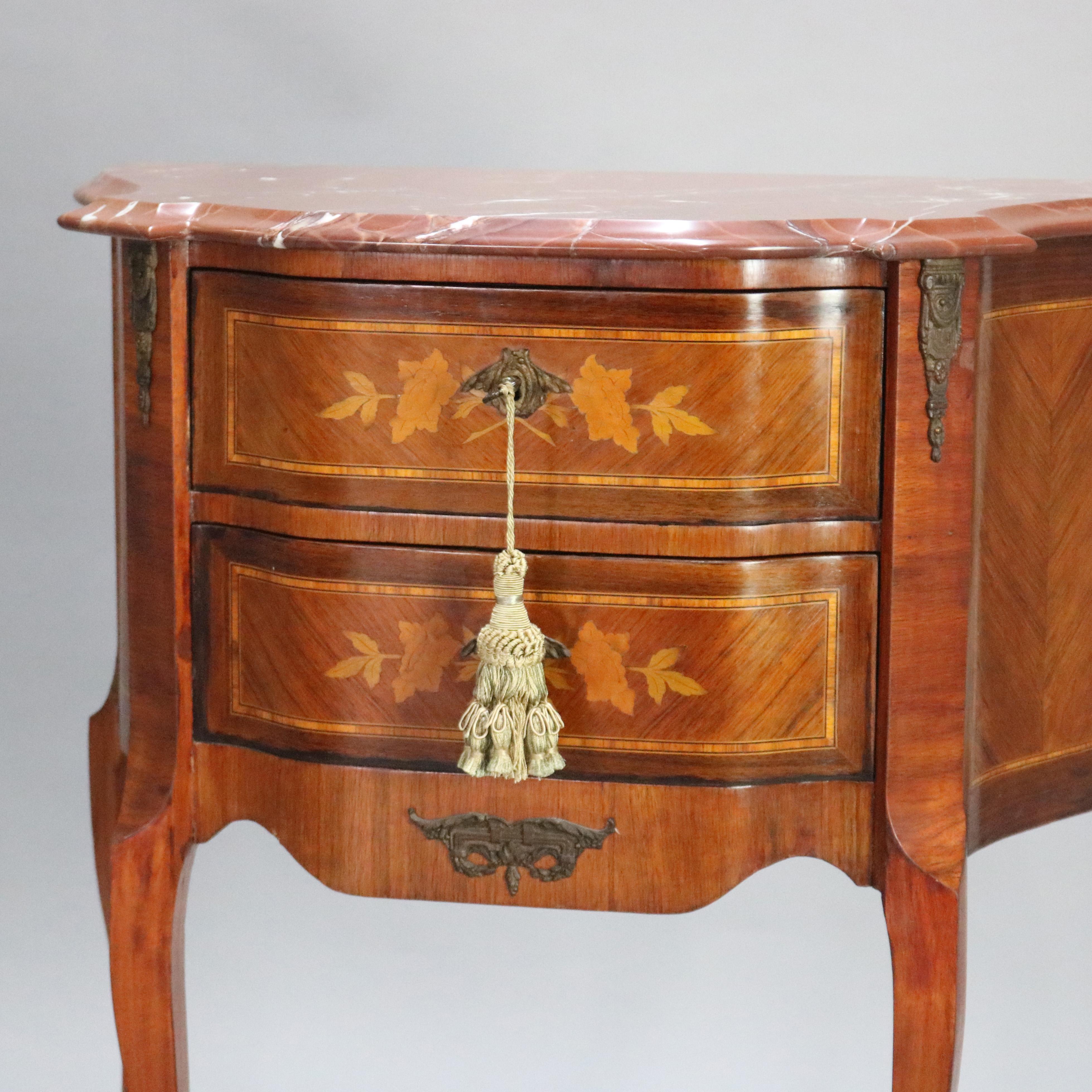 A vintage French Louis XVI style side stand offers shaped and beveled marble top surmounting double drawer case with satinwood banding and foliate marquetry, bookmatched sides, raised on cabriole legs, foliate ormolu mounts throughout, en verso