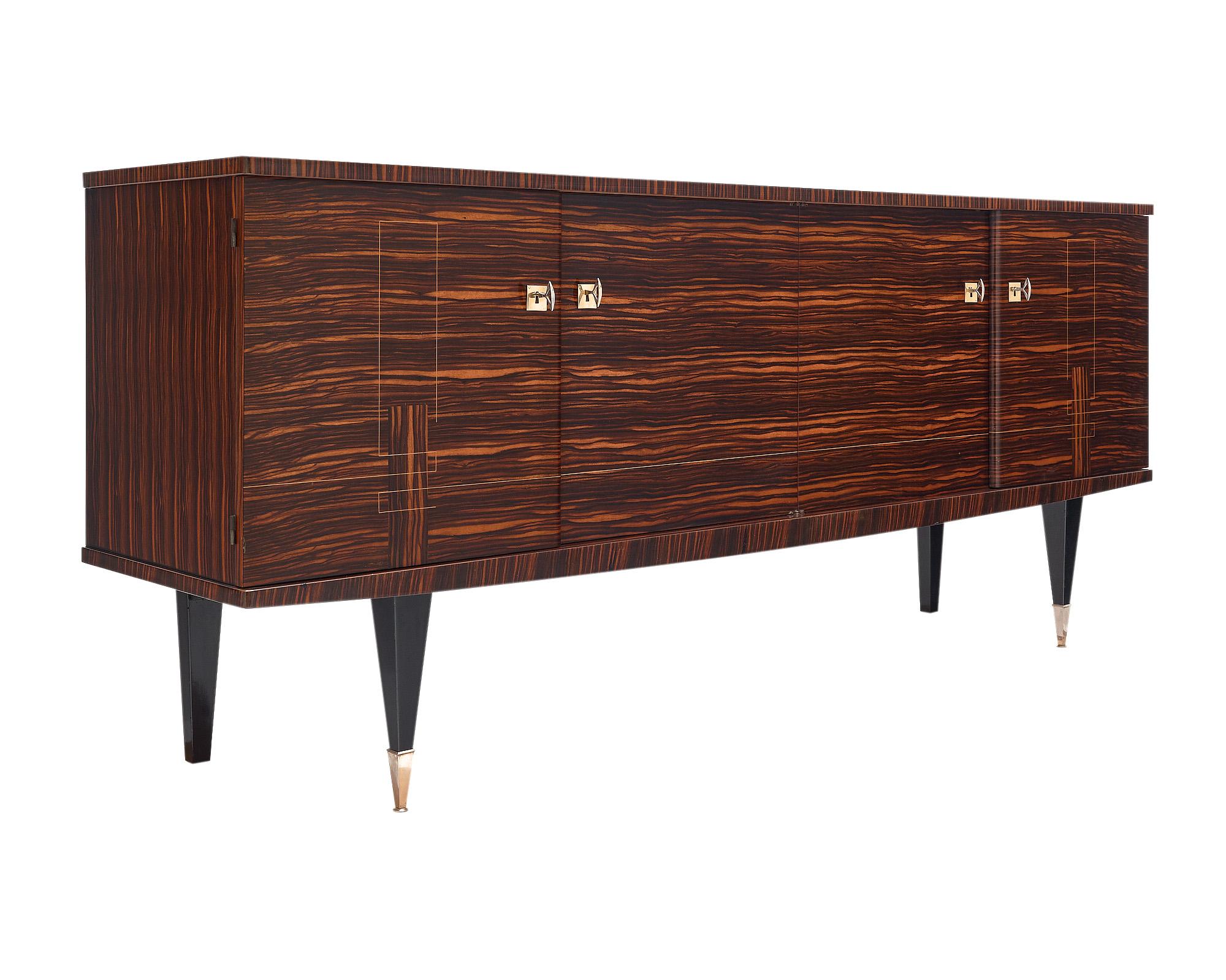 Buffet / Enfilade, in a classic French mid-century modern style and made of rare Macassar of ebony wood adorned with lemon wood inlays. The four doors, with their original brass working locks and keys, open up to an adjustable satin wood interior