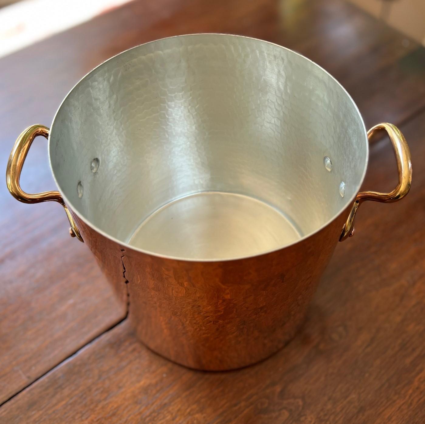 1940's vintage French hammered copper and tin lined stockpot with D-shape (anse) bronze hand grips projecting from a broad baseplate. Such pots were ordered and imported by the retailer Charles F. Lamalle (b. 1927 France - d. 1991, NYC). Lamalle was