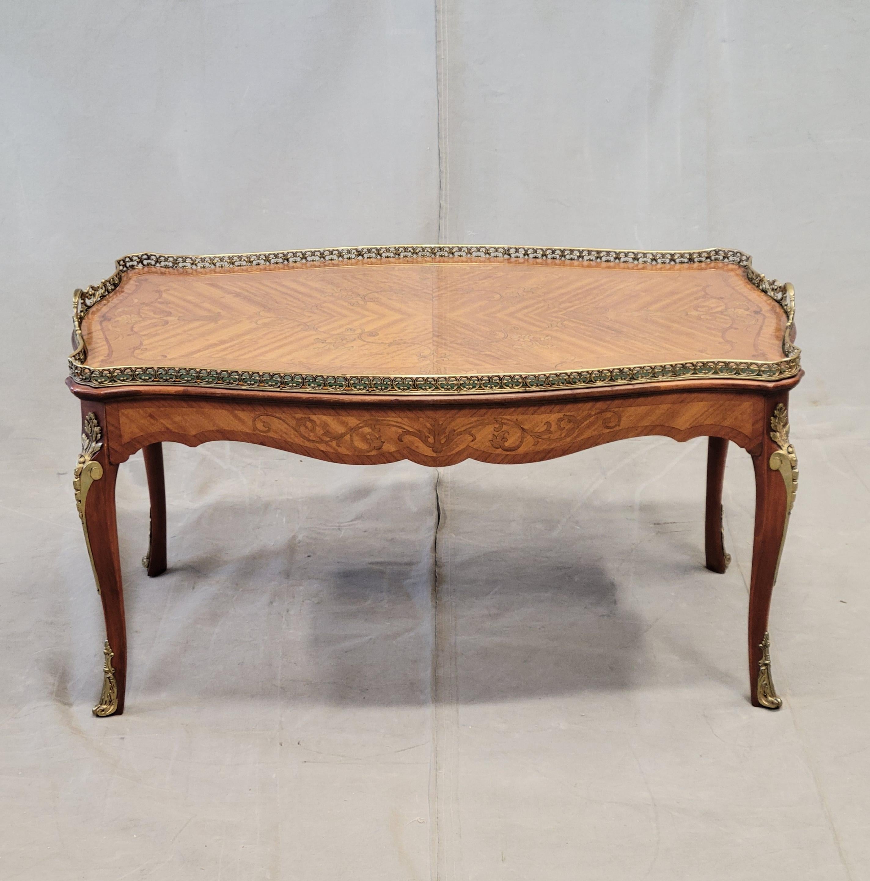 Un elegante tavolino da caffè francese d'epoca in mogano intarsiato con ormeggi in ottone. Il piano del tavolo ha un'impiallacciatura di intarsio ed è circondato da una galleria e da maniglie in ottone traforato. Il grembiule del tavolo è