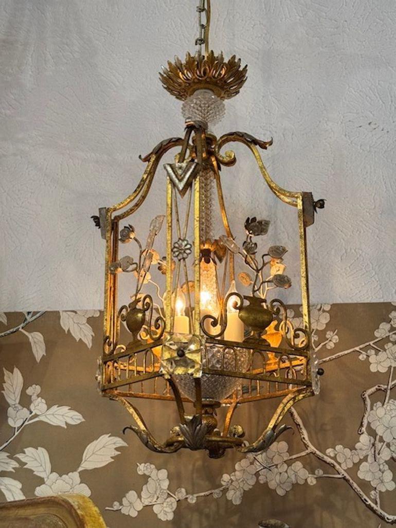 This vintage French Maison Bagues style pendant chandelier features a luxurious design with gilt Toile and crystal accents, reminiscent of elegant French decor. The chandelier is crafted in a gilt toile, enhancing the beauty of the crystal elements