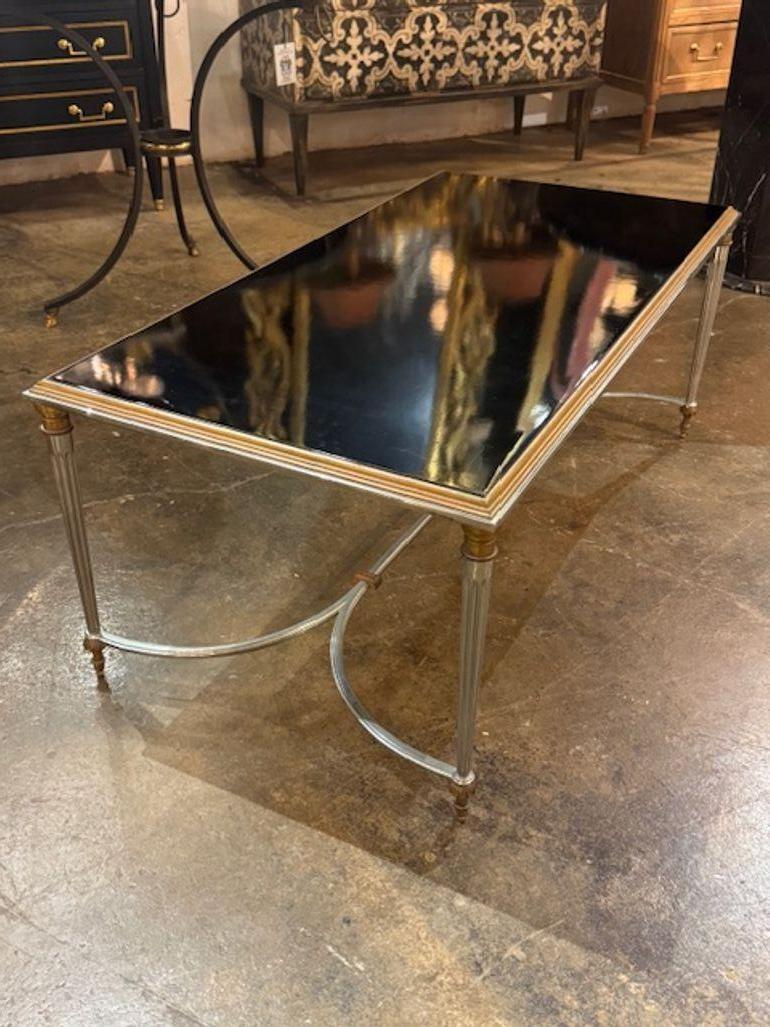 La mesa de centro francesa vintage Maison Jansen de acero, latón y cristal negro desprende un estilo retro con un acabado pulido y líneas limpias clásicas. Fabricada con materiales de alta calidad y atención al detalle, esta mesa de centro combina