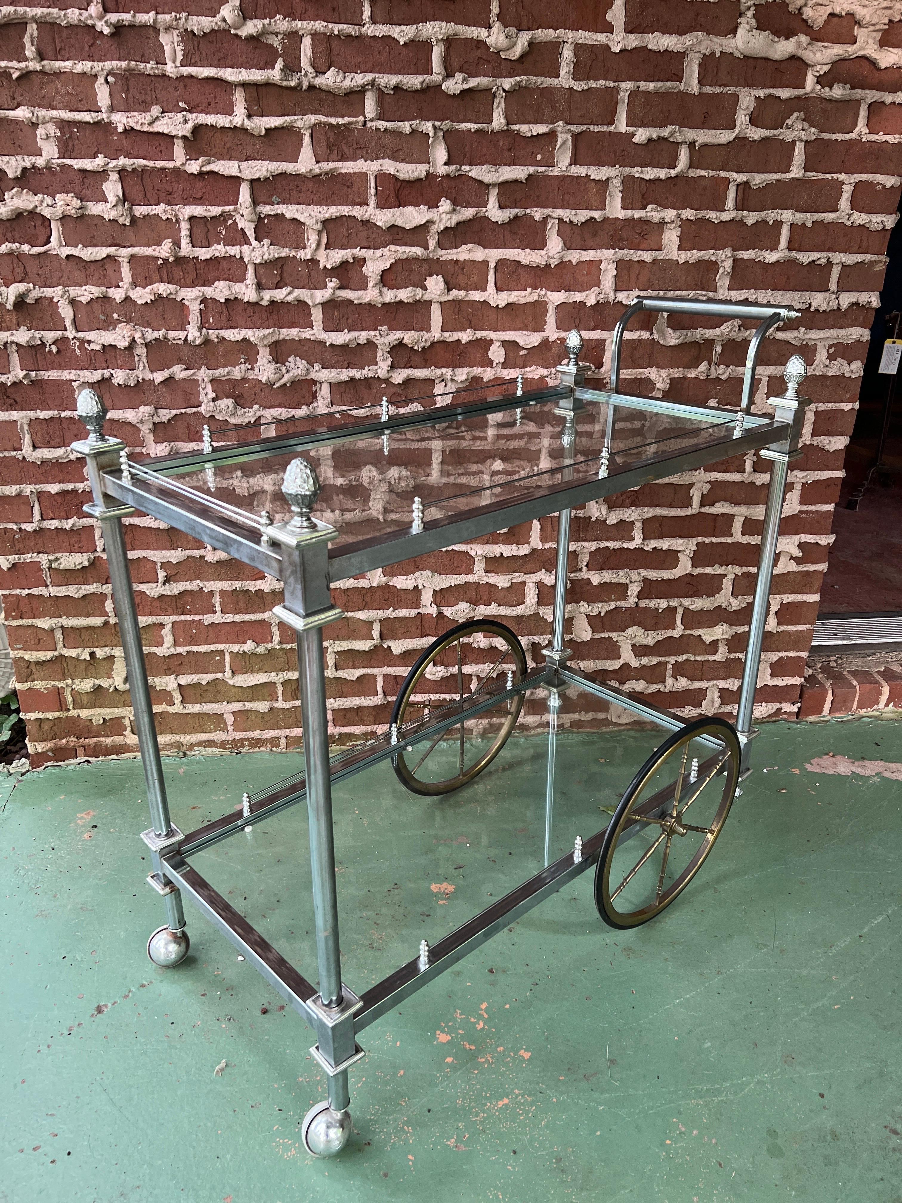 French, Circa early 20th century.

A very well crafted French rolling bar cart in the style of Maison Jansen. The cart features a mixed metal frame, steel or chrome body and brass acorn finials. 

The bar has a wired edge trim on both levels and
