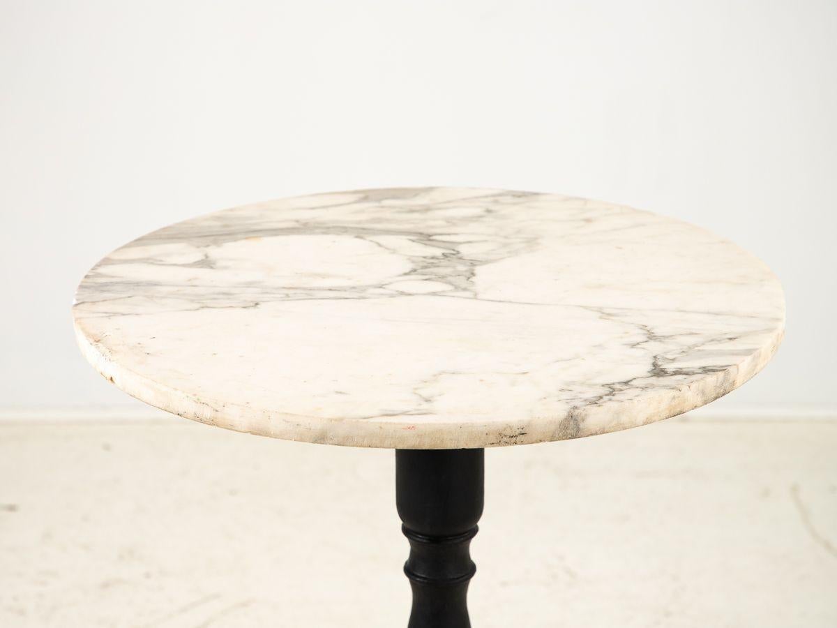 The French pub table embodies a captivating blend of rustic charm and refined elegance. Its black-painted iron base exudes durability and strength while adding a touch of vintage allure. The round marble top showcases exquisite veining patterns,