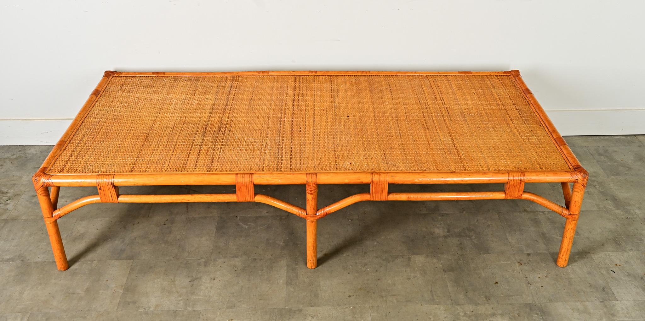 Table basse en rotin vintage français (années 1970), dans le style modernisme tropical des Designs Eleg & Minet, synthétisant l'élégance décontractée du style côtier avec la sophistication cosmopolite. Sur le large sommet, la bande de roseaux tissés