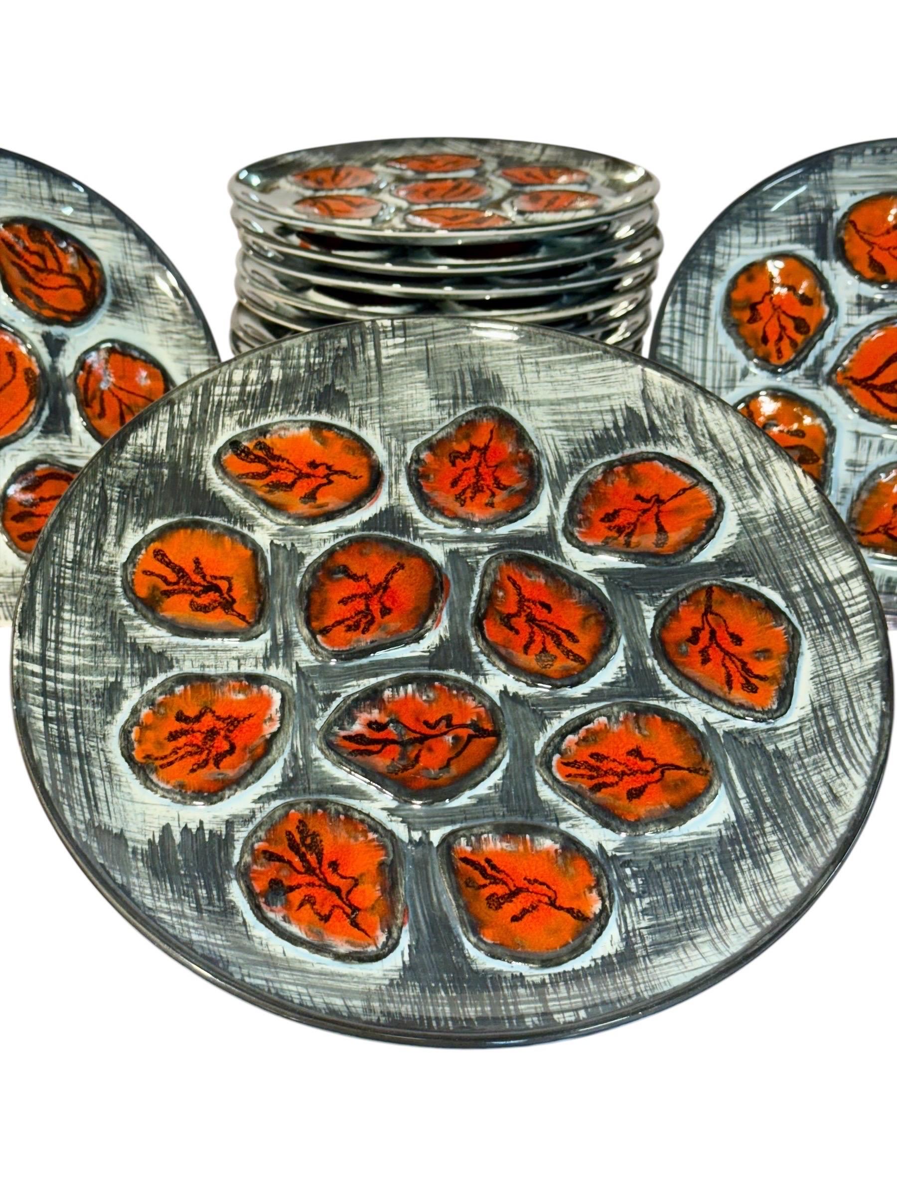 This exceptional vintage French seafood service comprises twelve oyster plates and one large matching round serving platter, all handcrafted by the renowned M.B.F.A. workshop in Pornic, France. Entirely hand-painted (Peint à la main), the set