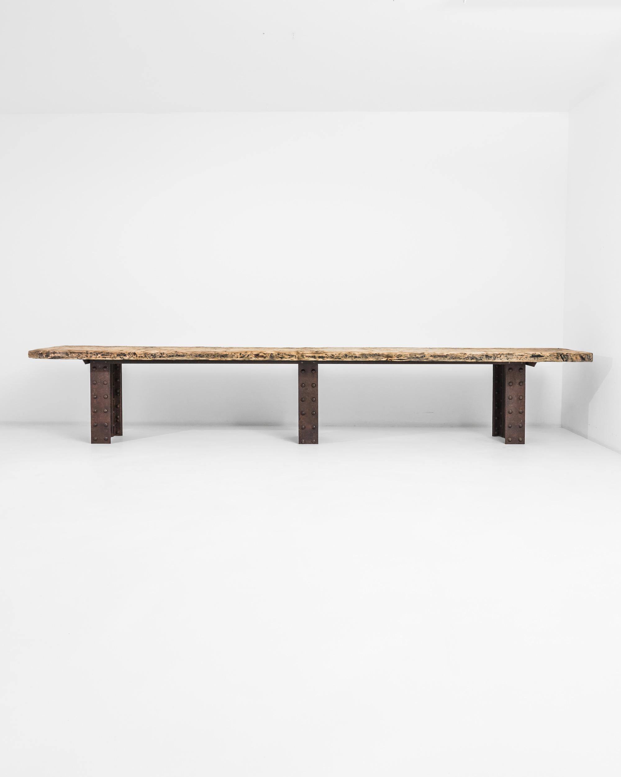 This show-stopping table epitomizes the stark, muscular beauty of the industrial aesthetic. Made in turn of the century France, the table legs are formed out of slices of a giant metal girder, of the kind used in engineering and construction. A