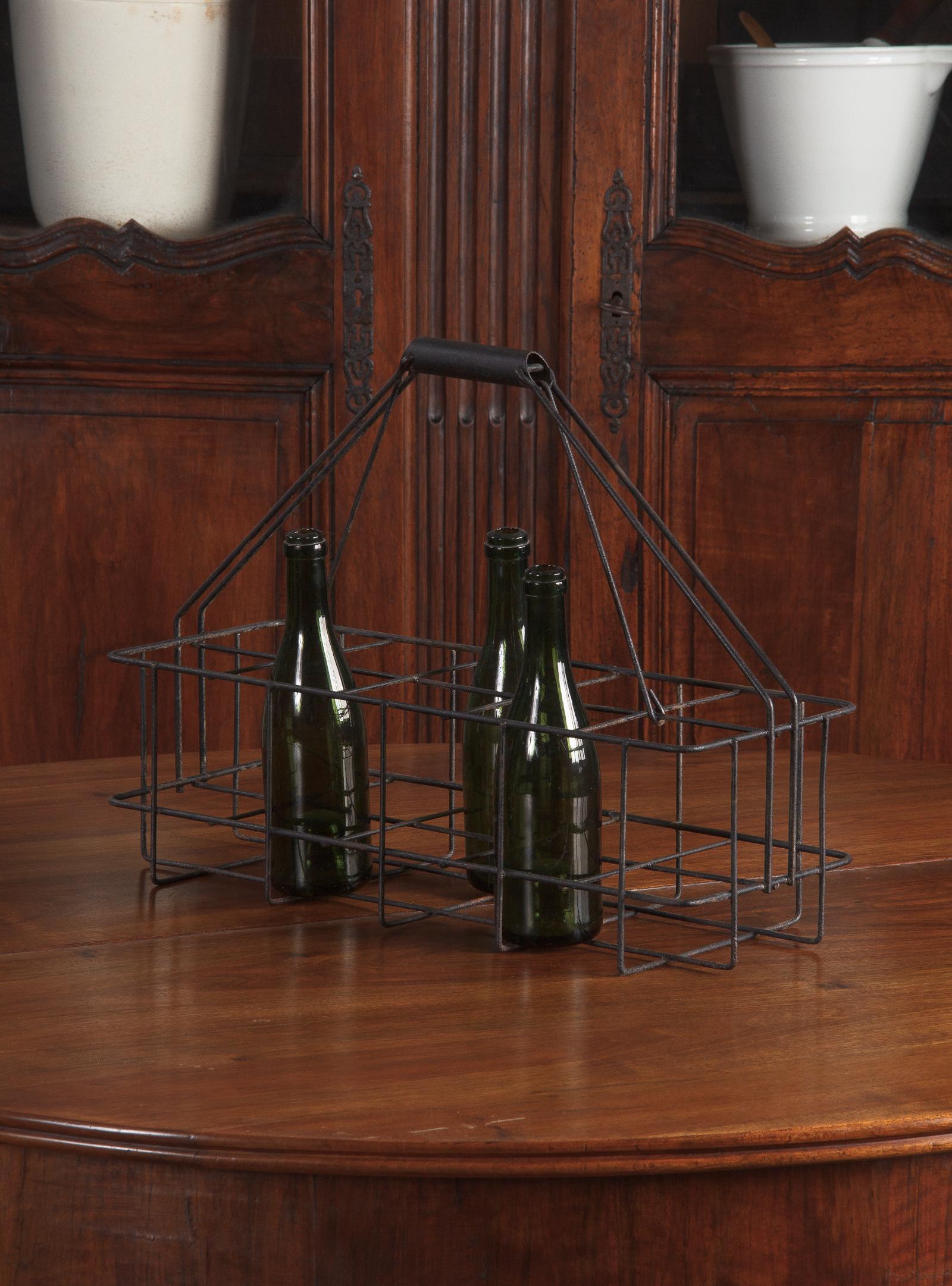 A large vintage iron metal bottle holder painted black, French, circa 1940. Thick iron wire frame in elongated shape with reinforced handle. Holds ten bottles in two rows of five with dividers between and a tubular handle at the top connected to the
