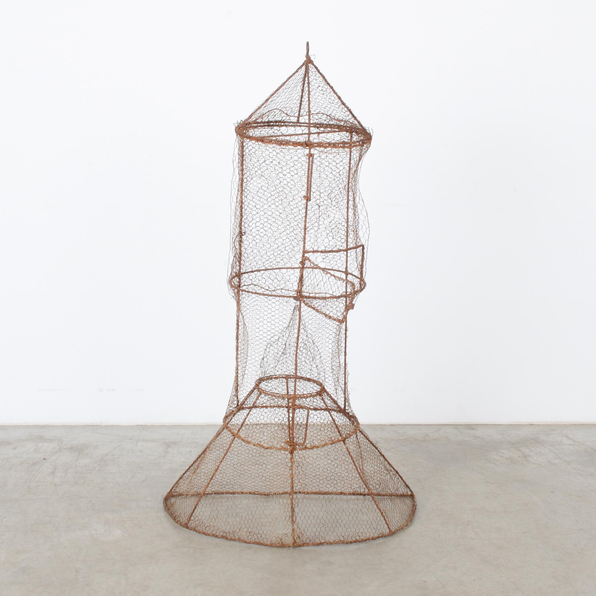 This fish trap was made in France, circa 1970, and will be a charming decorative piece with its beautiful rusted patina. Constructed with metal rods and wire mesh, the trap features a funnel and a cone on each end. The trap door is located in the