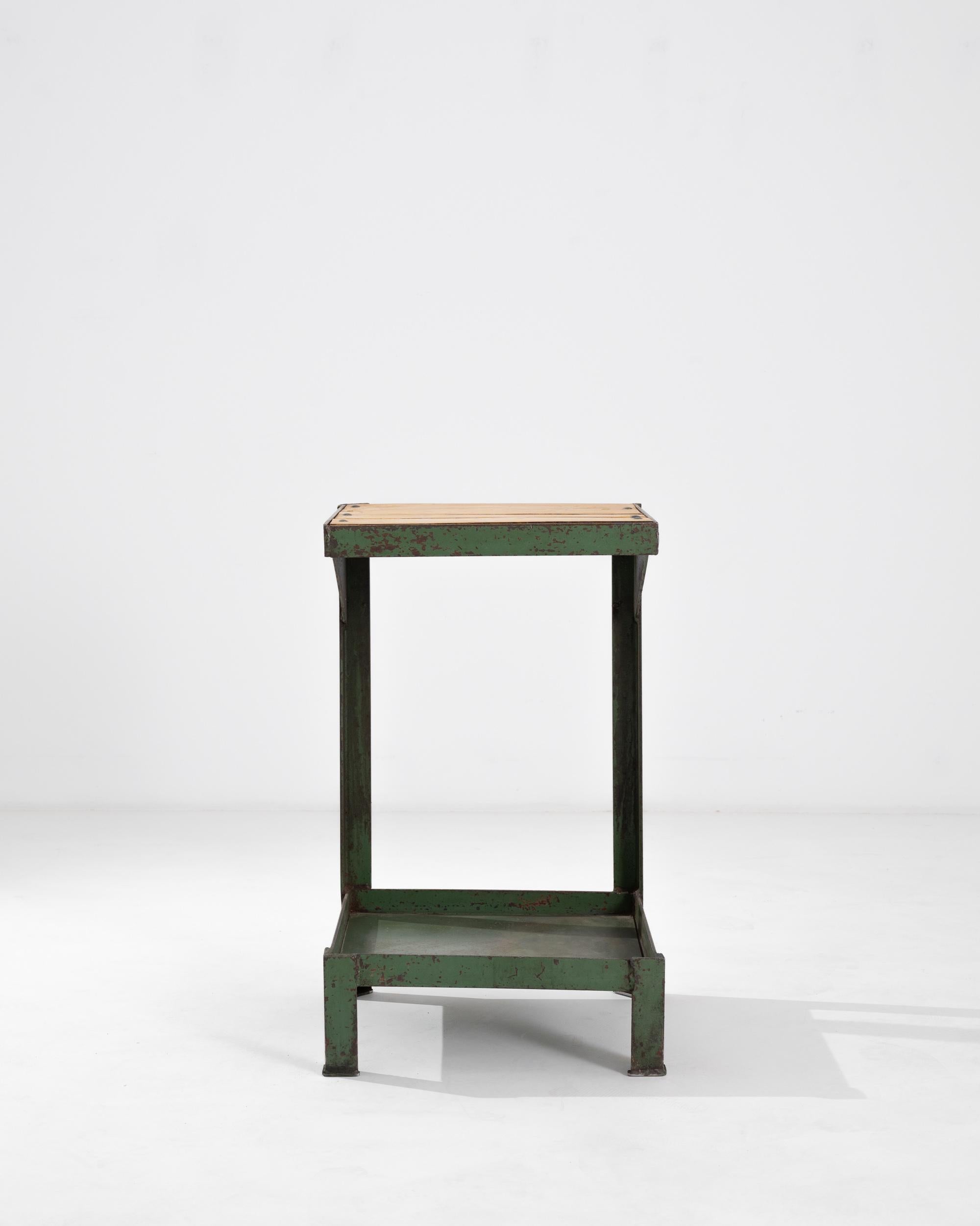 Dieser Vintage-Tisch setzt einen auffälligen Industrial-Akzent. Die im 20. Jahrhundert in Europa hergestellte Form ist streng architektonisch: Stahlträger stützen ein Paar Plattformen, die mit Metallbändern eingefasst sind. Quadratische Beine