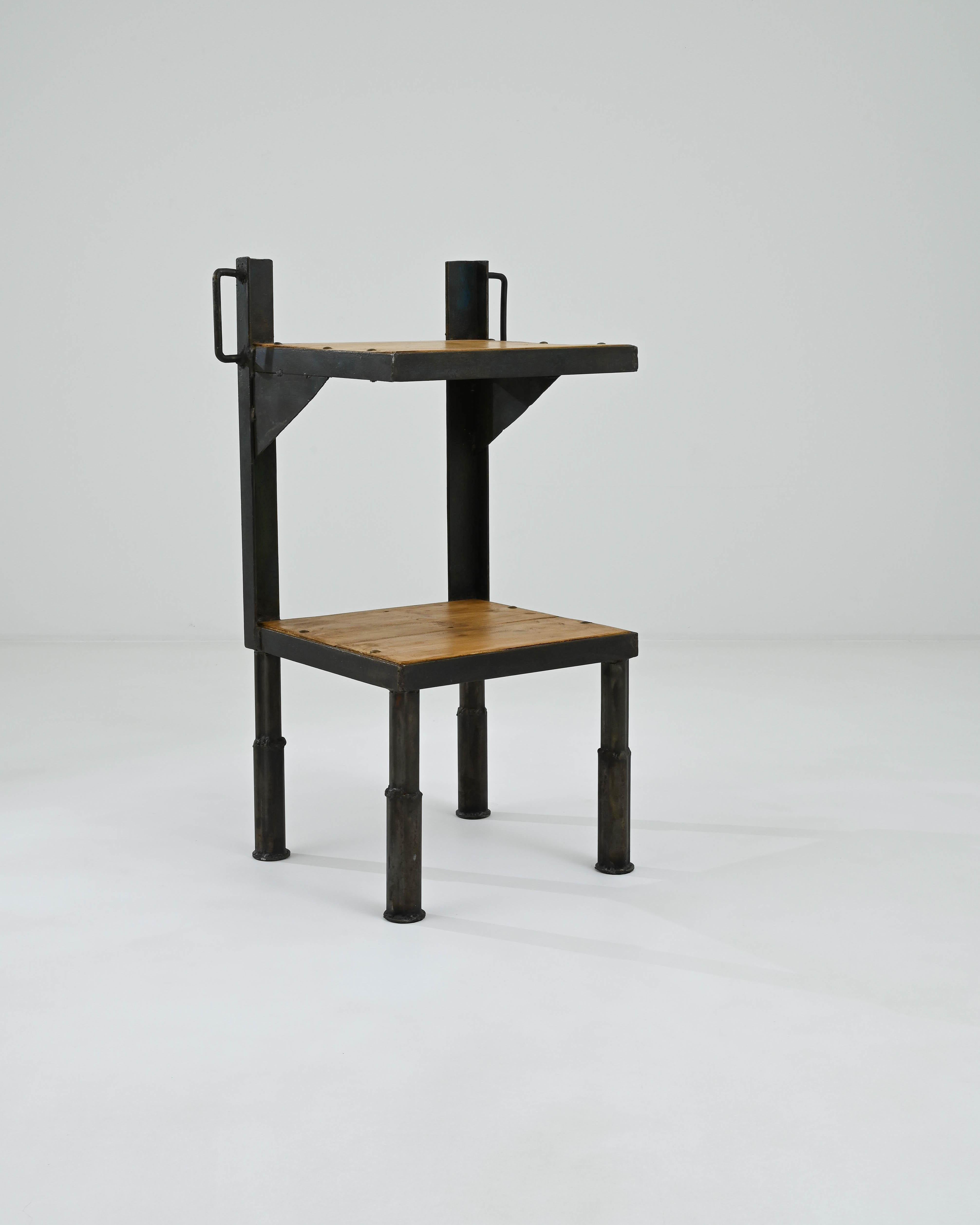 Dieser Vintage-Tisch setzt einen auffälligen Industrial-Akzent. Die im 20. Jahrhundert in Frankreich hergestellte Form ist streng architektonisch: Stahlträger stützen ein Paar Plattformen, die mit Metallbändern eingefasst sind. Quadratische Beine
