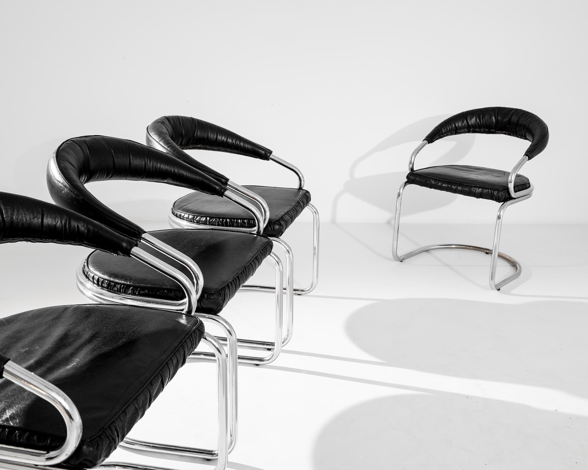 This set of four vintage armchairs was produced in France, circa 1970. An iconic original black leather upholstery dresses tubular steel. Audaciously designed, the tubular armature offers an elegant lightness and a decidedly modern profile, while