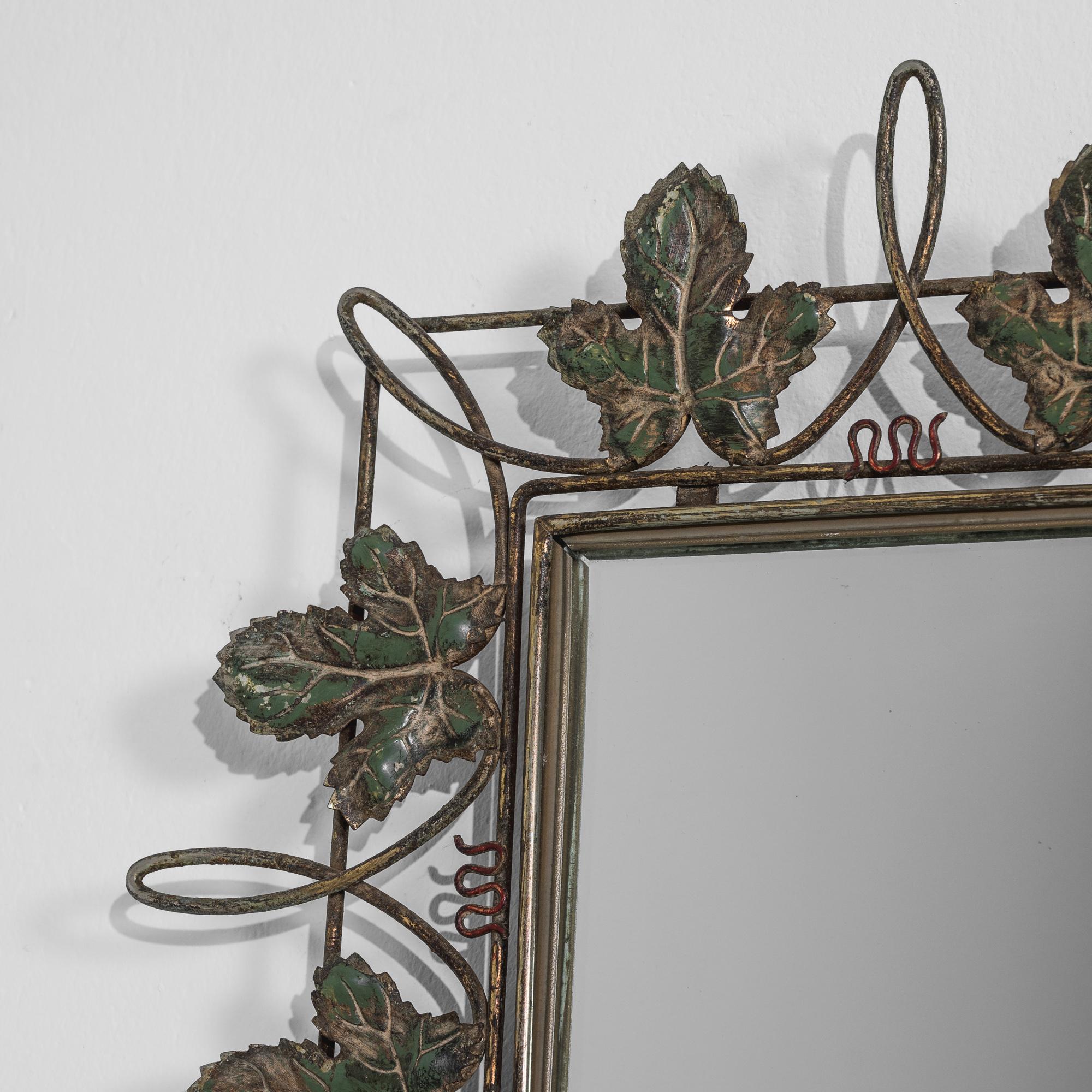 The vivacious design of this 20th century mirror evokes the green vineyards of the French countryside. A rectangular mirror is bordered by a design of veined leaves and looping vines; delicate metal squiggles suggest the inquisitive tendrils of new