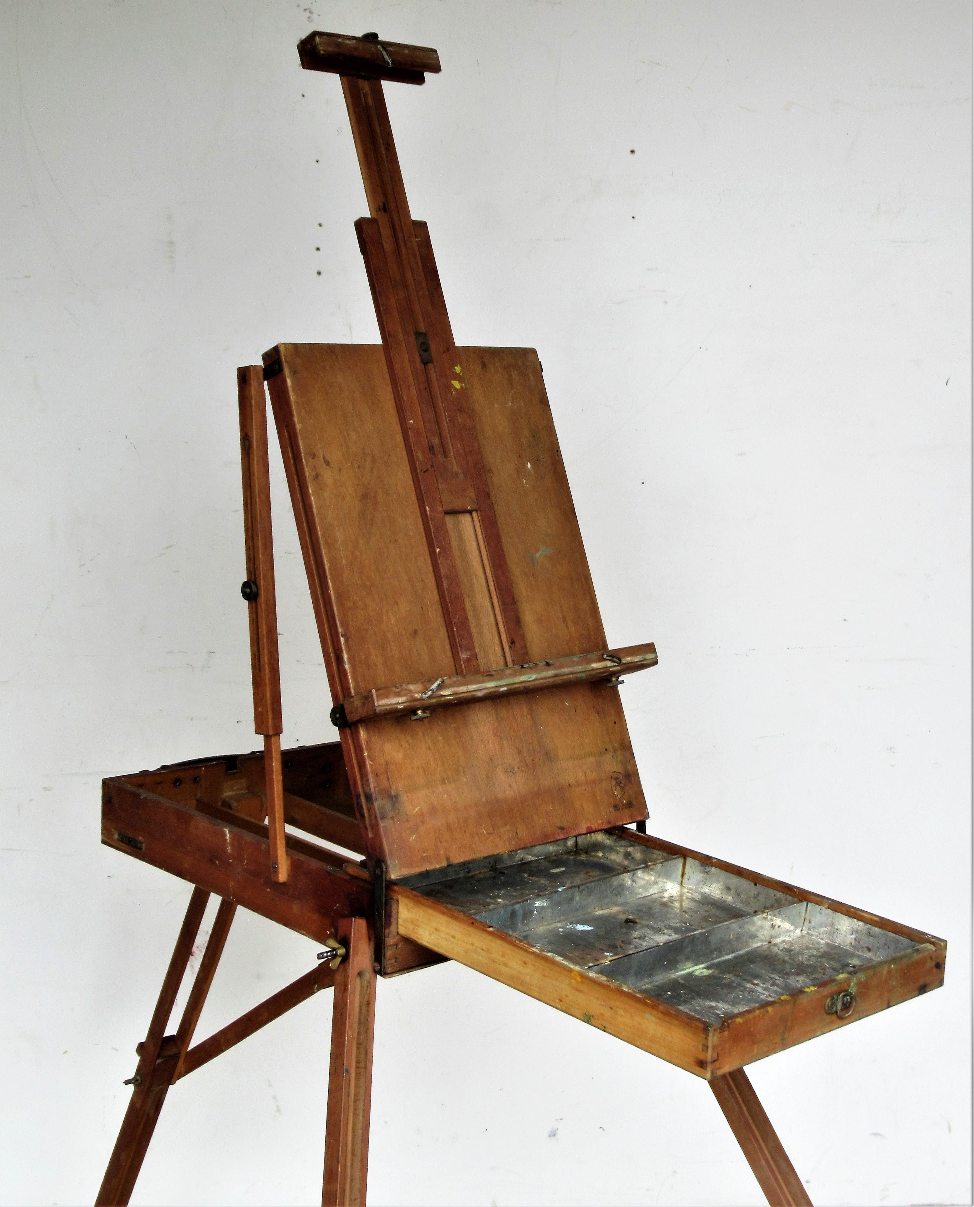 Vintage portable painters box with adjustable height and angle three leg floor easel for traveling / Plein air painting. Overall nicely aged original old patina color to wood and brass fittings with all parts present and working. Grumbacher - made