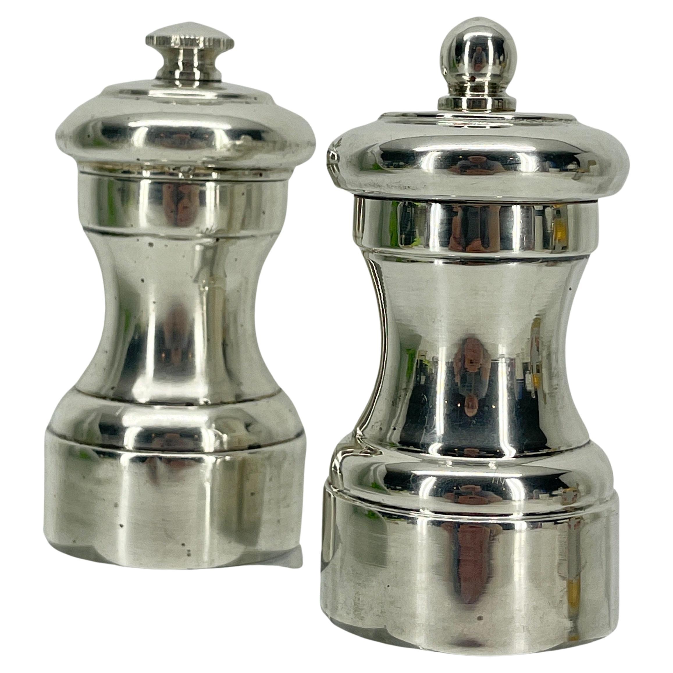 Mid-Century Modern salt and pepper shaker set in the style of the esteemed design firm Peugot in France, circa 1960. The sterling silver pair features hourglass forms, stepped bodies with finials at the top of each in lustrous sterling silver. The