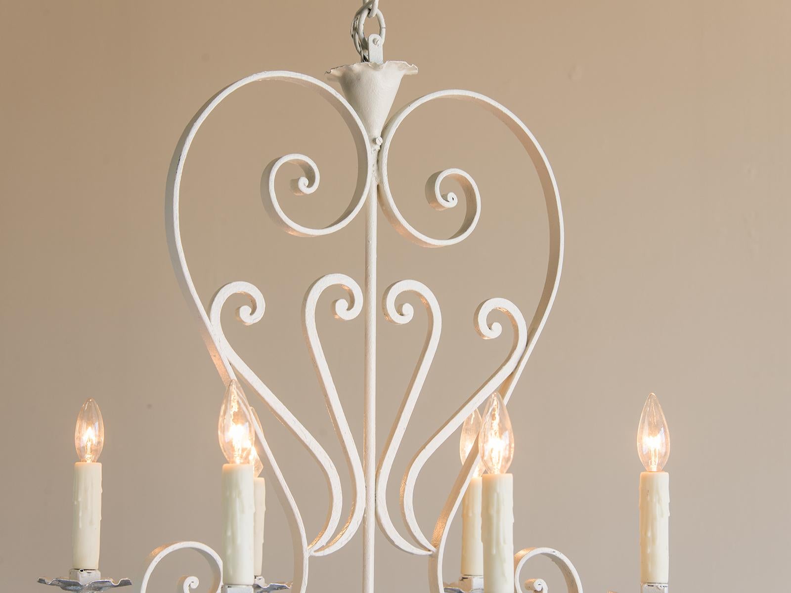 The unusually tall and slender profile of this vintage French chandelier from France circa 1950 is visually striking as it updates a nineteenth century design in a clever manner. The wooden horizontal support was coated with silver leaf while the