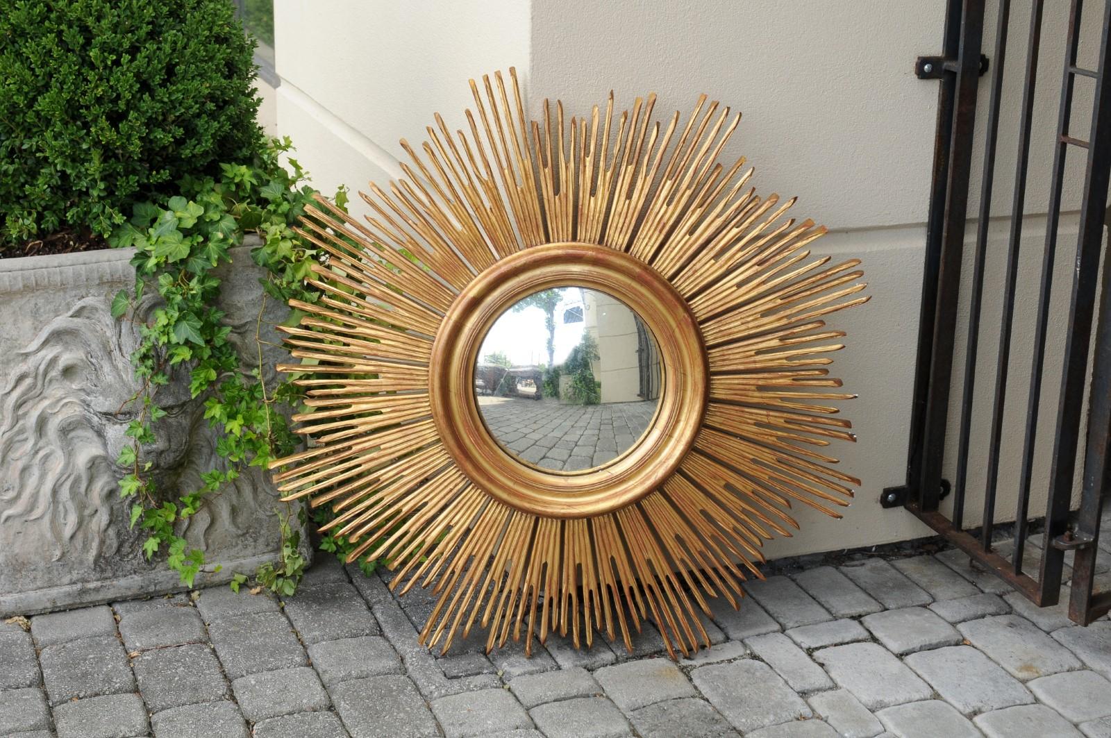 A French vintage giltwood sunburst mirror from the mid-20th century, with radiating rays and convex mirror. Born in France during the mid-century period, this stylish sunburst mirror captures our attention with its radiating presence, showcasing