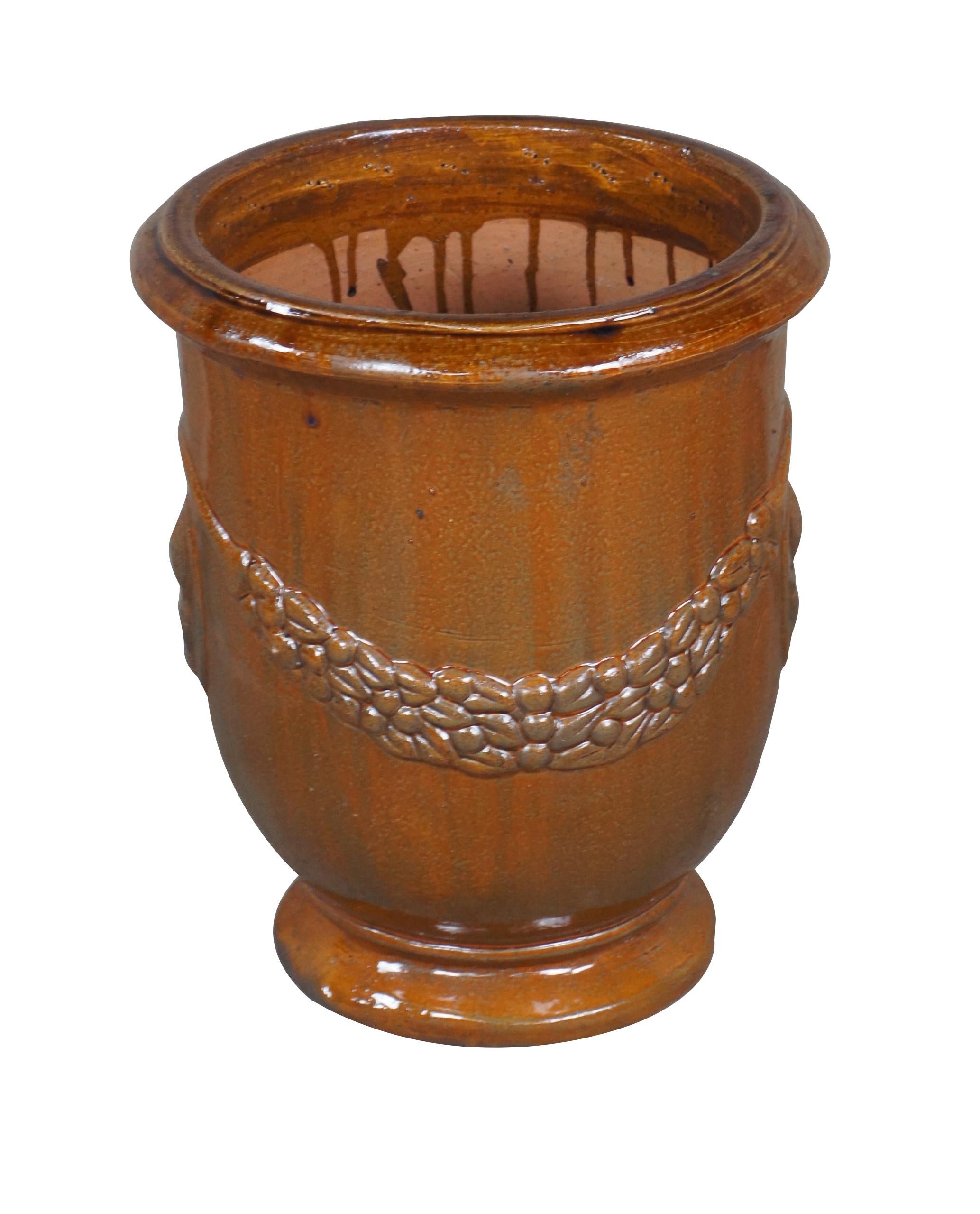 A lovely French clay fired pot in brown glaze with wreath detail and medallion along each side. The raised medallion features a bush in a pot.   The beautiful glaze has varying shades of brown.  Drip hole at the center of base.

Dimensions:
14