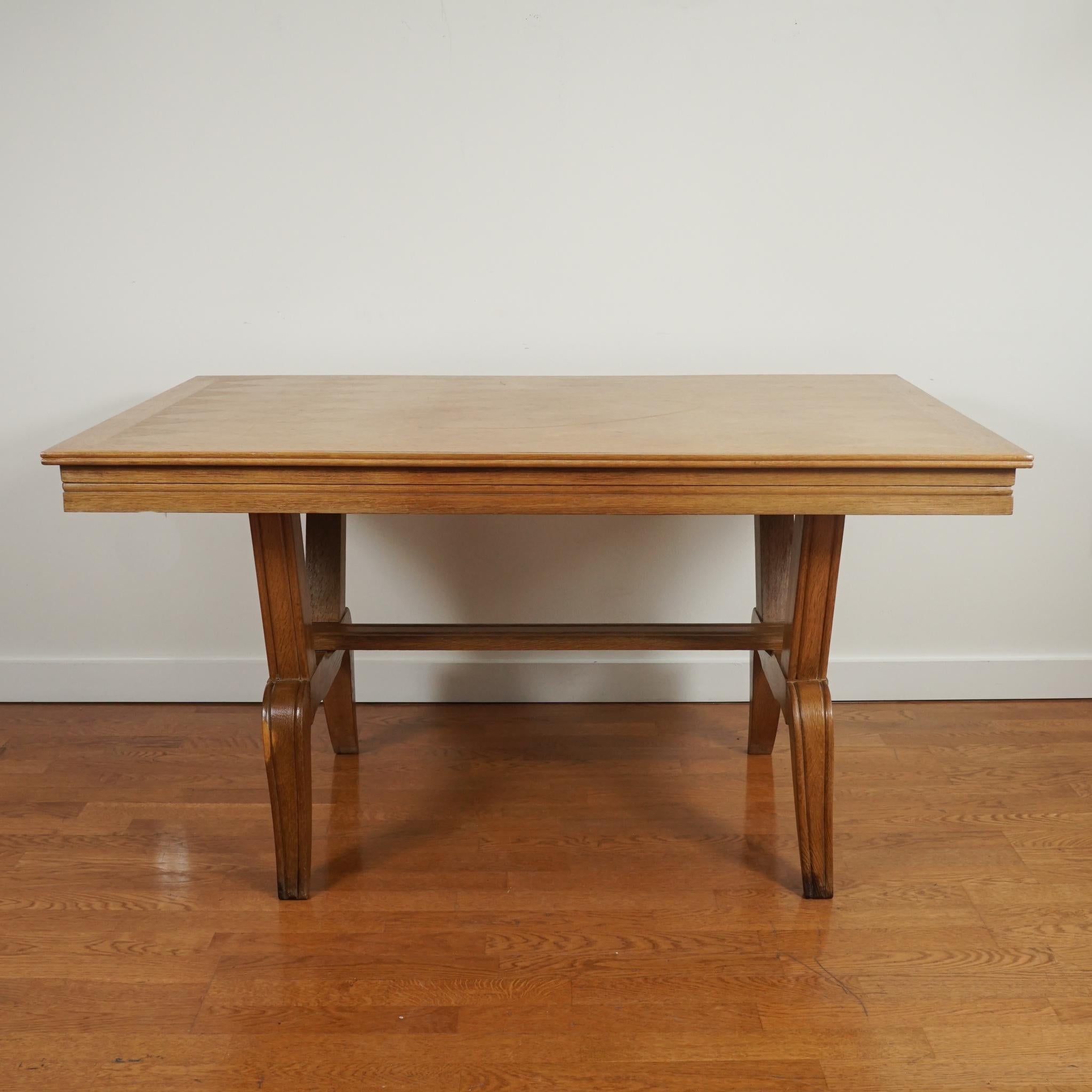 The French oak dining table, shown here, is made of solid oak and features a diamond-patterned veneer top and stylized trestle base with stretcher. Made in the 1950s, it has beautiful aged patina with little only minimal signs of wear. The design