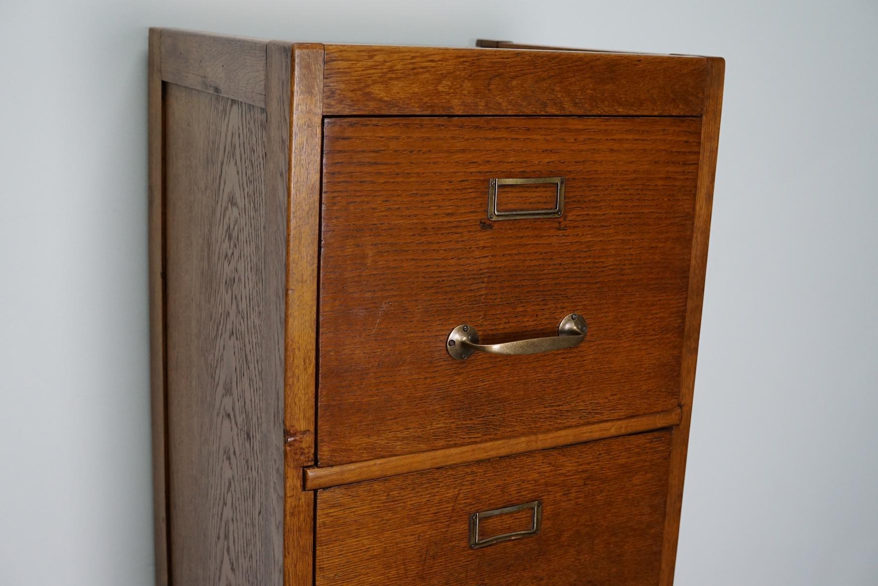 This oak filing cabinet with brass hardware was made in the early 20th century in France. It was very well made and it remains in a good antique condition. The interior dimension of the drawers are: D W H 35 x 38 x 10 / 28 cm.