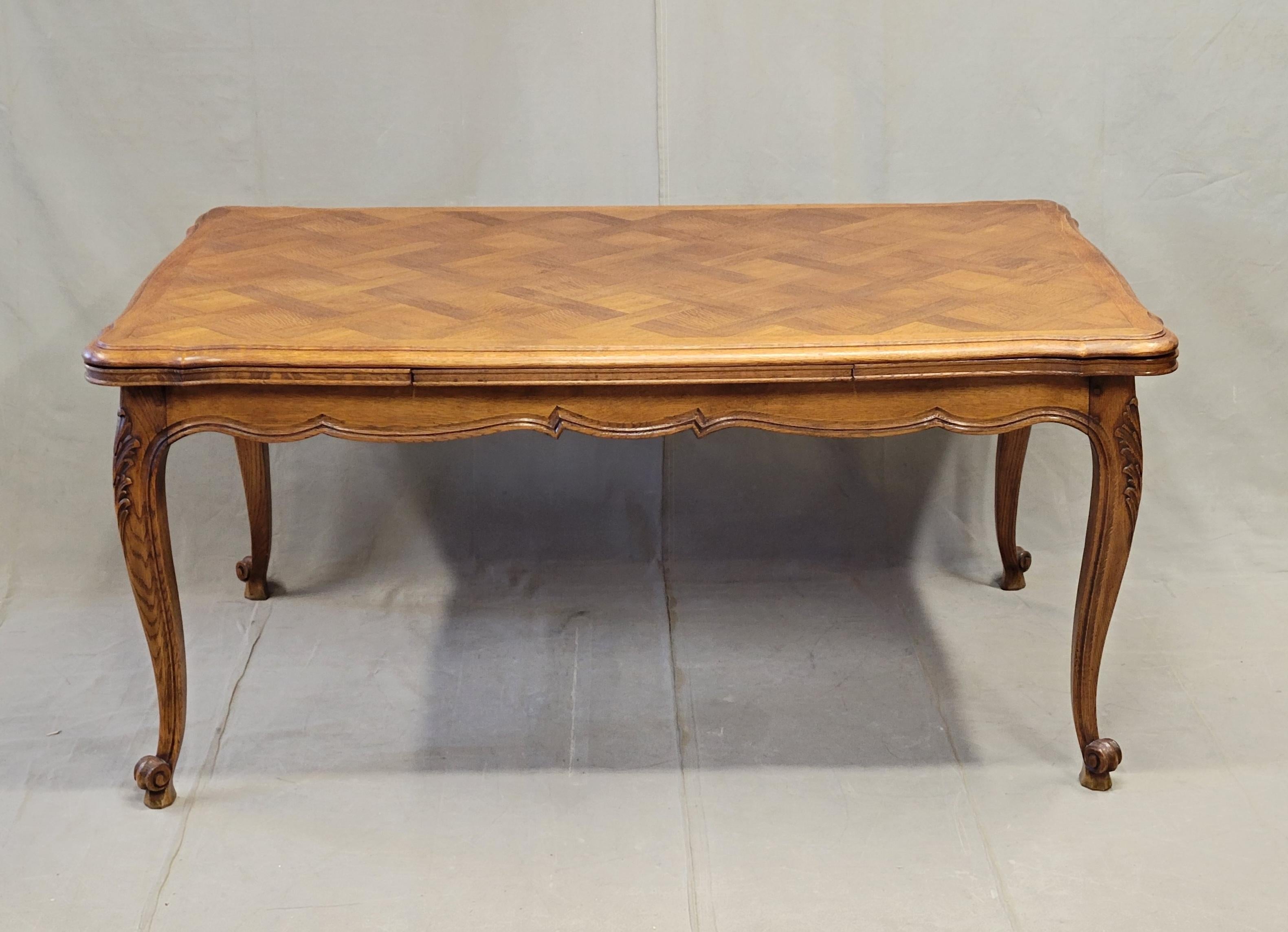 An elegant and functional vintage French oak parquet top draw leaf table with cabriole legs. This classic design allows for storage of leaves underneath the table top with easy to pull out for additional seating space. The rich parquet top adds a