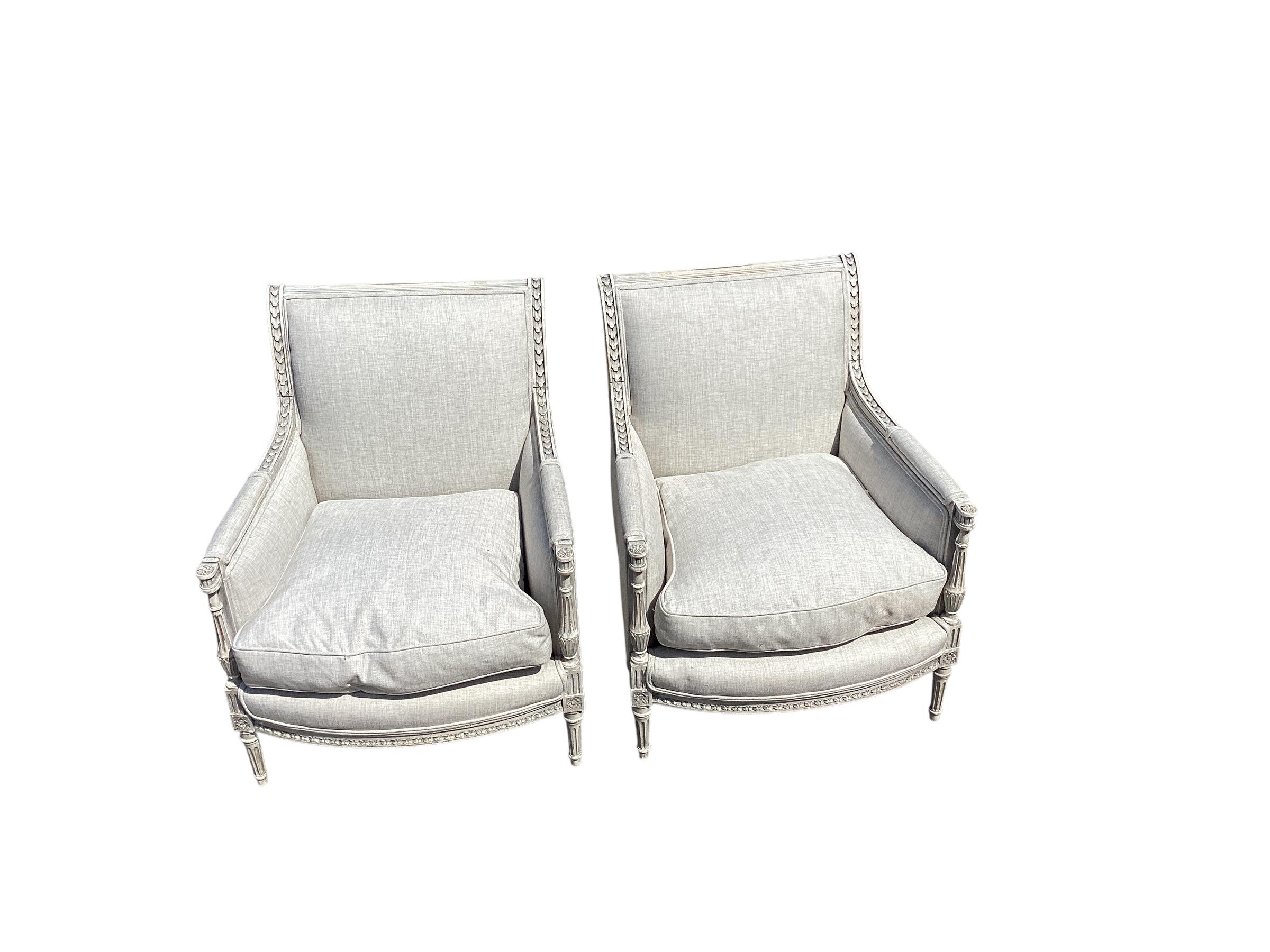 Paire de chaises bergères peintes de style Louis XVI du début du 20e siècle. Cette paire de  Fauteuils de style Louis XVI en France. Chaque fauteuil présente des coussins remplis de duvet, un dossier de forme rectangulaire avec une traverse
