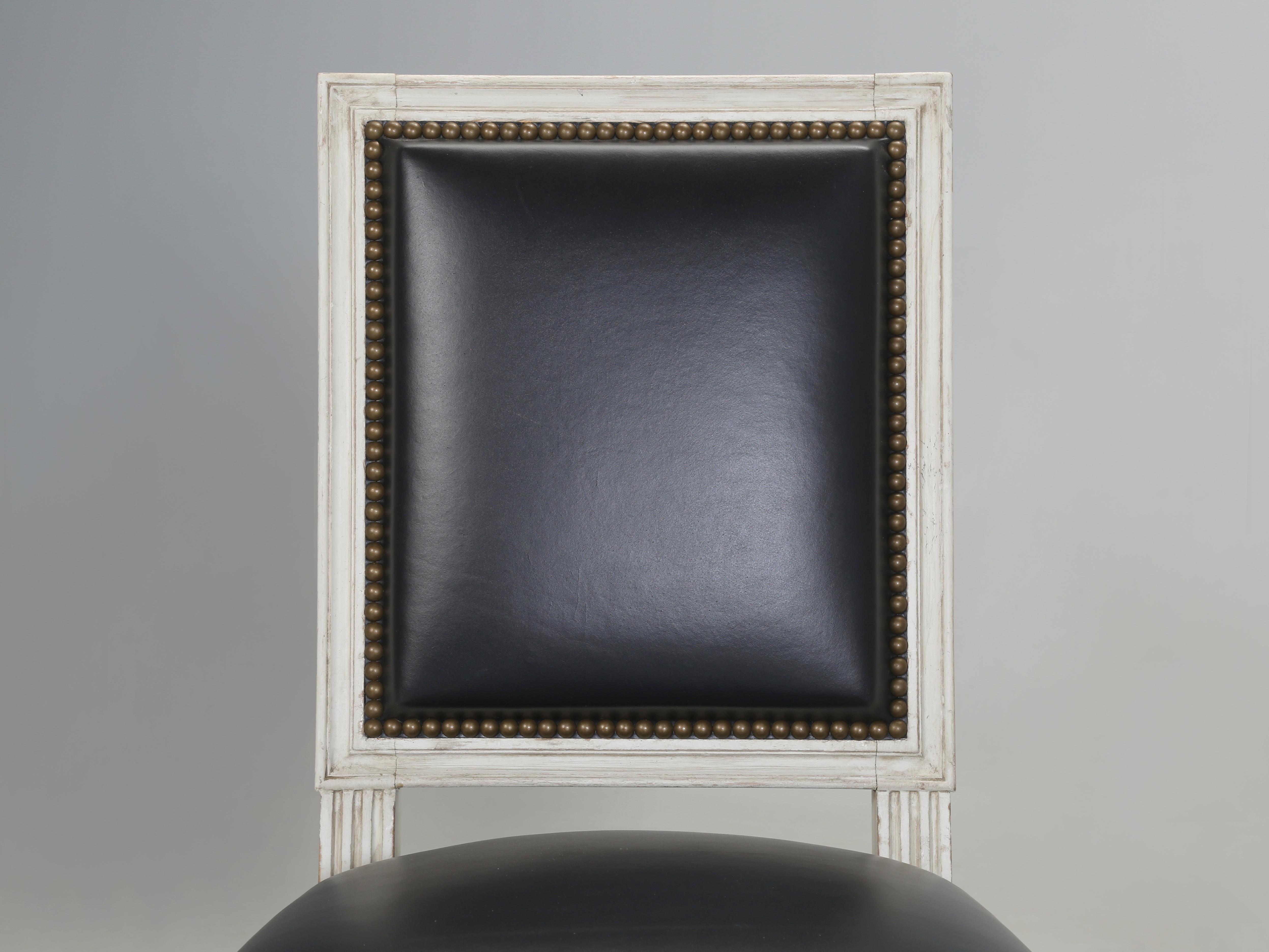 Vintage French Louis XVI Style Dining or Desk Chairs in Old Plank's Distressed White Paint and covered in Black Leather. During the restoration process, everything was executed by old school standards. Meaning, 9-step antique painted finish, 8-way