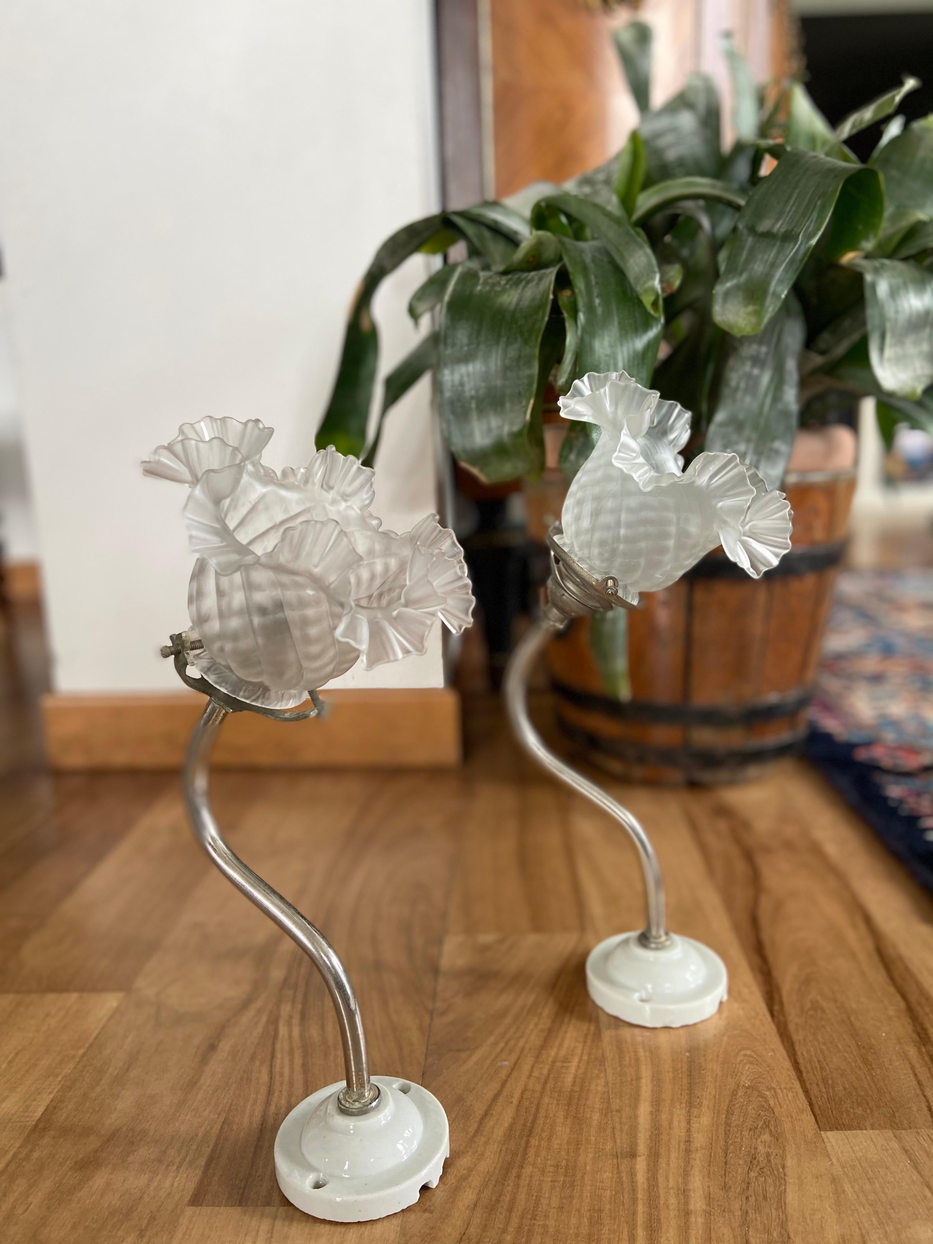 Ein Paar Wandlampen aus Metall mit handgefertigten Glasblumenschirmen und Keramiksockeln.
Frankreich, um 1920.