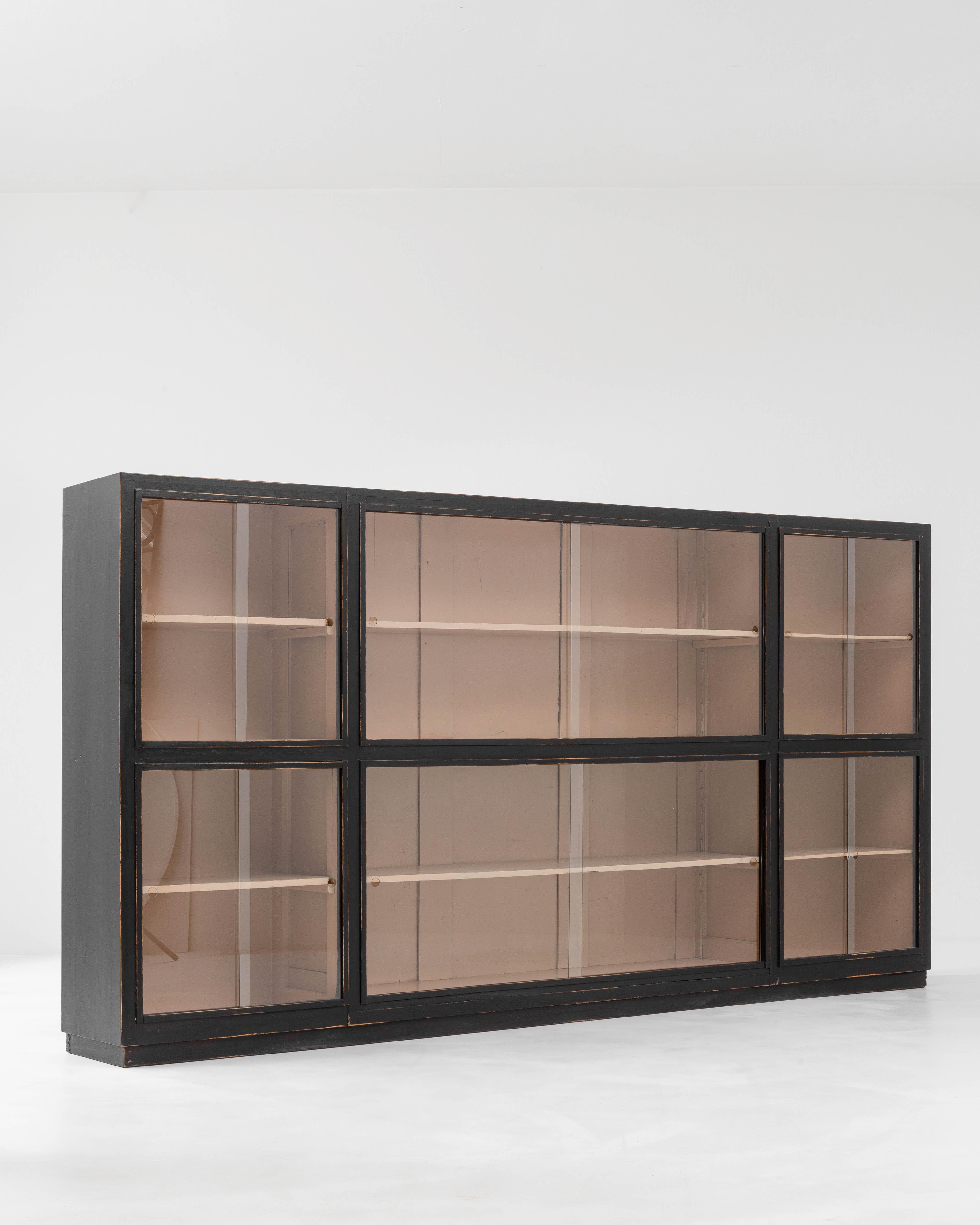 Exhibiting a sleek modern elegance, this minimalist vitrine was designed in 20th-century France. The rectangular, black-patinated base encloses glass panels, dividing the interior into six sections. The black lines of the exterior frame stylishly