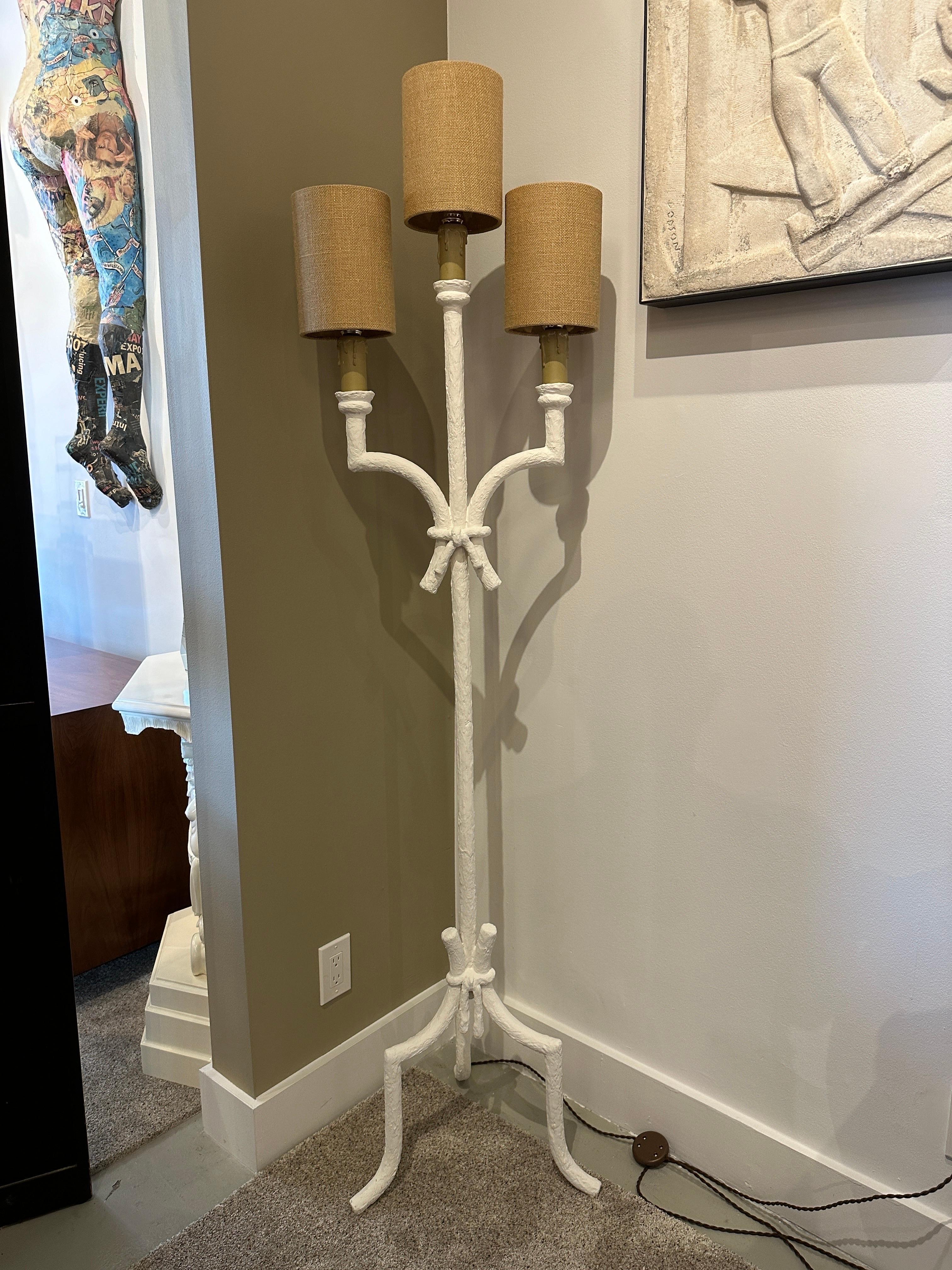 This Giacometti inspired French plaster tri-legged and three arm torchiere style floor lamp is finished in a rustic French plaster in off-white. Having the original raffia shades ( in vintage used condition), have been Rewired to US standards with