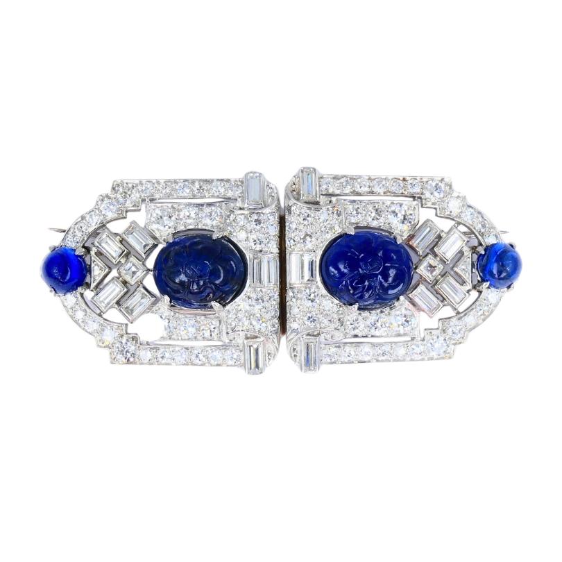 Ein Paar französische Vintage-Clips aus Platin mit Diamanten und geschnitztem Saphir.
Das Design der Clips ist auf Symmetrie und starke Linien ausgerichtet. In der Mitte jedes Stücks befindet sich ein geschnitzter blauer Saphir mit einem floralen