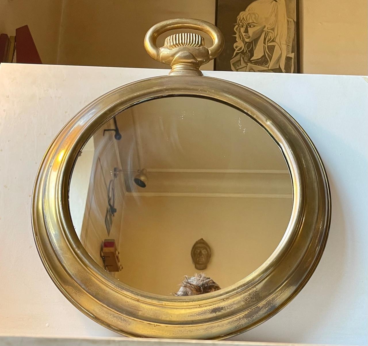 A round brass pocket watch mirror made in France during the 1950s. Its frame is made from solid brass that has developed a Natural patina. Its suitable for bathrooms, small alcoves or in your entrance reception area. Dimensions: 49 W x 63 H x 6.5 D