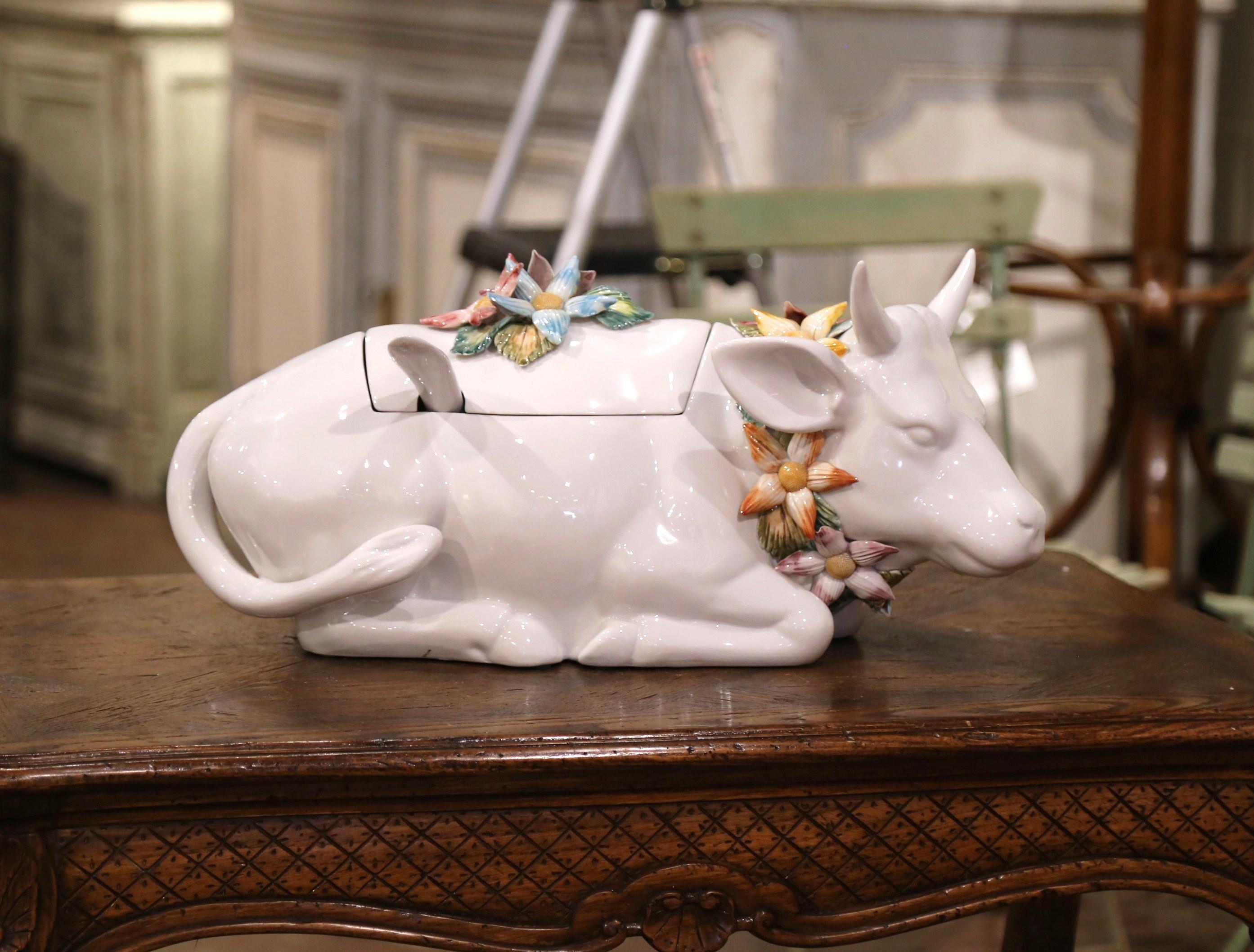Decorate a dining table with this elegant and colorful Majolica centerpiece. Crafted in France circa 1980, the ceramic tureen is shaped as a cow resting and decorated with a necklace of flowers round the neck. The lid, embellished with a handle made