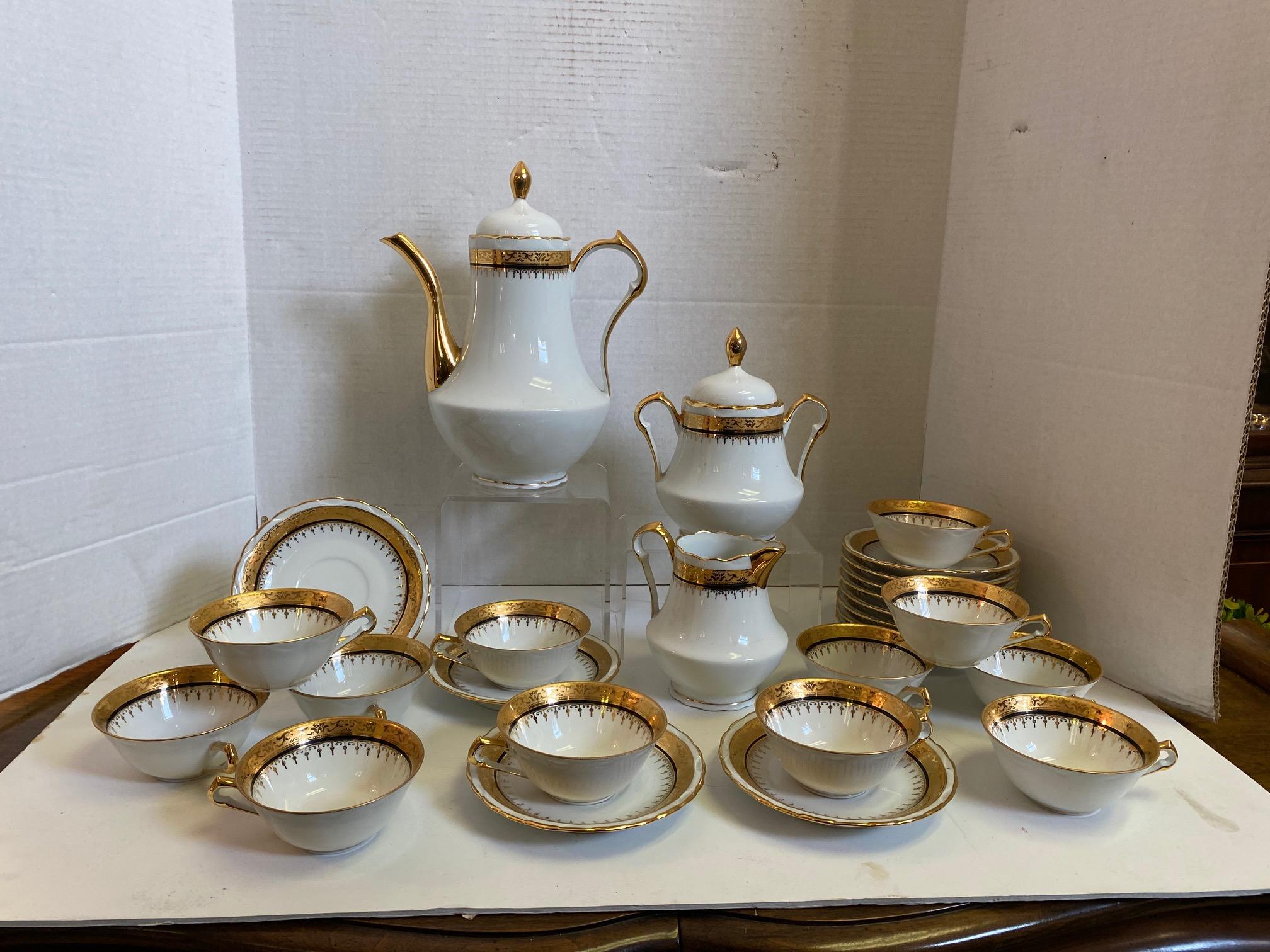 French porcelain tea set. Hand-decorated with 24-karat gold paint accented with a thin black banding. Set includes: teapot with lid, sugar bowl with lid, creamer and 12 tea cups and saucers. Painted on the bottom of each piece is, 