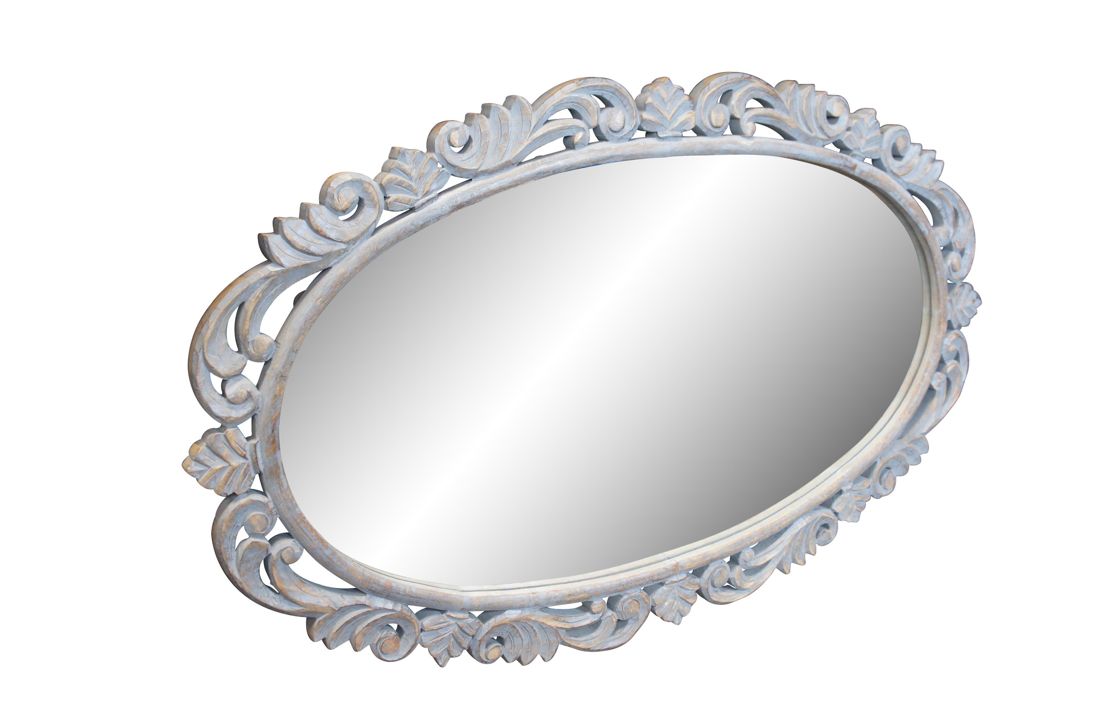 Un grande specchio da parete ovale d'epoca con una cornice in legno grigio, invecchiato e afflitto, traforata e intagliata con un motivo a fogliame e acanto di ispirazione provinciale francese. Può essere appeso in verticale o in
