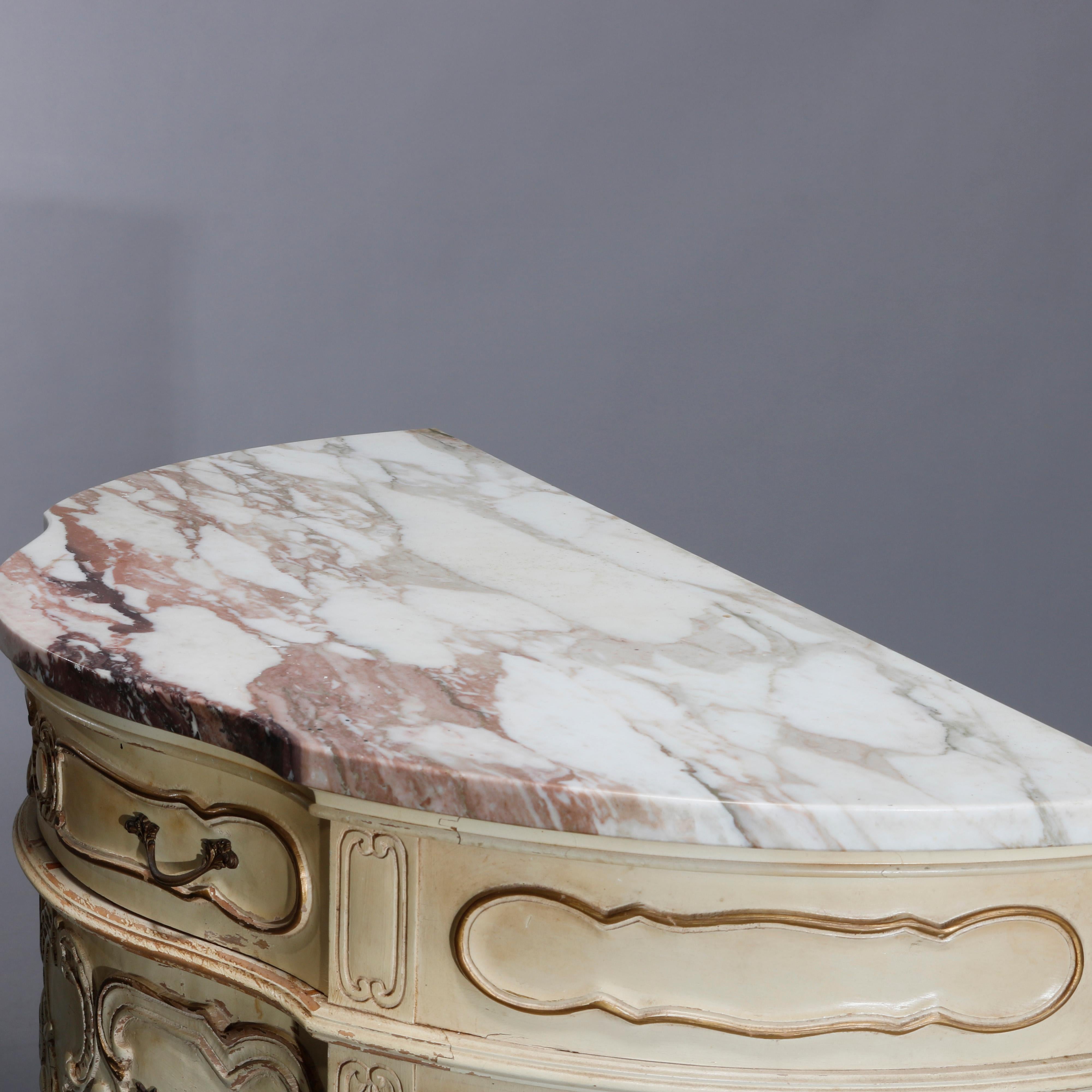 A vintage French Provincial commode offers marble top over painted decorated wood case in demilune form having three drawers, pierced apron, paneled sides with floral reserves and applied gadroon, scroll and foliate decoration, raised on scroll form