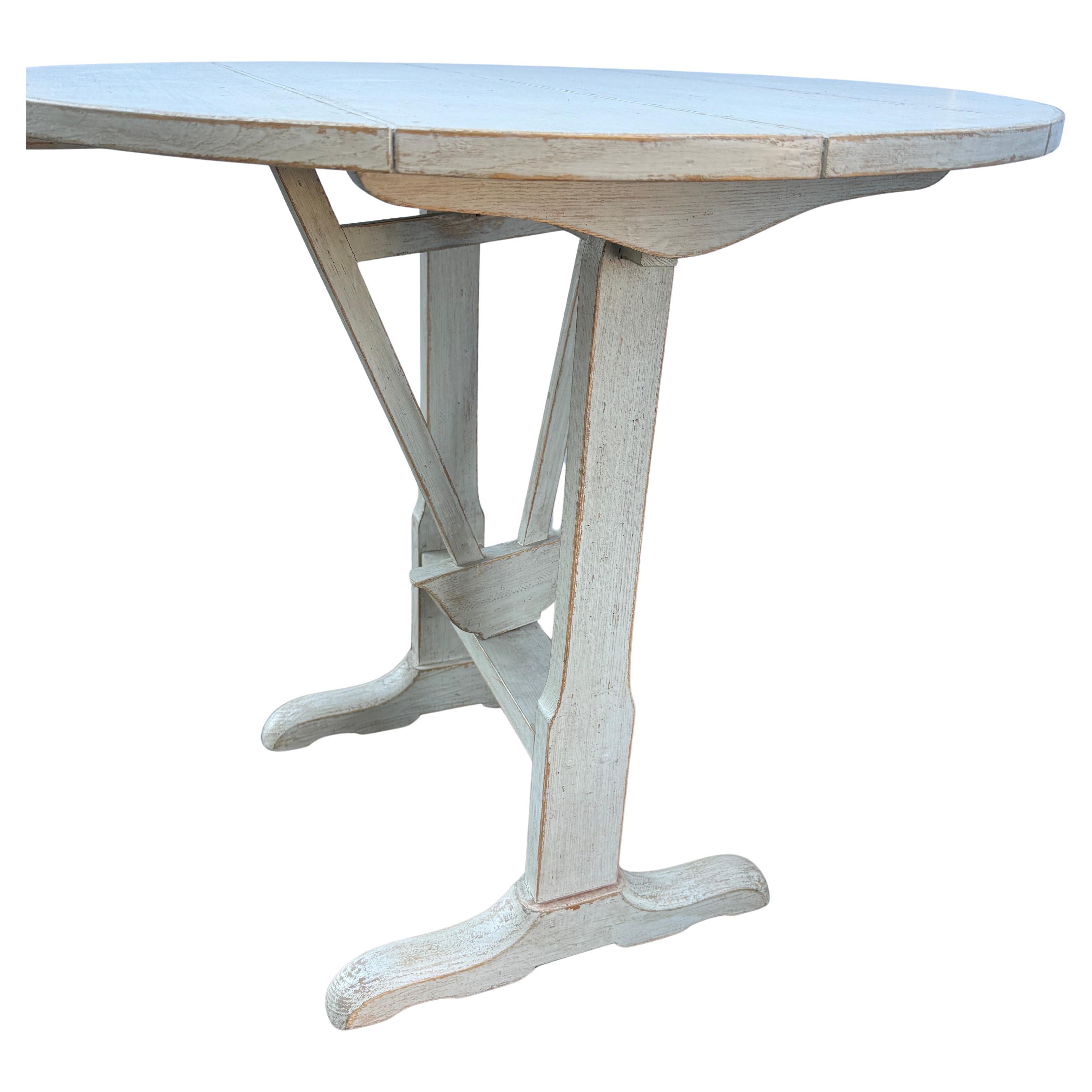 Tilt-Top Round Wine Tasting Table, France

Vintage French wine tasting low table, with a Gustavian painted patina with folding top, secured by a swinging gate. The trestle base is supported by arched sledged feet. Wonderful addition to any formal or